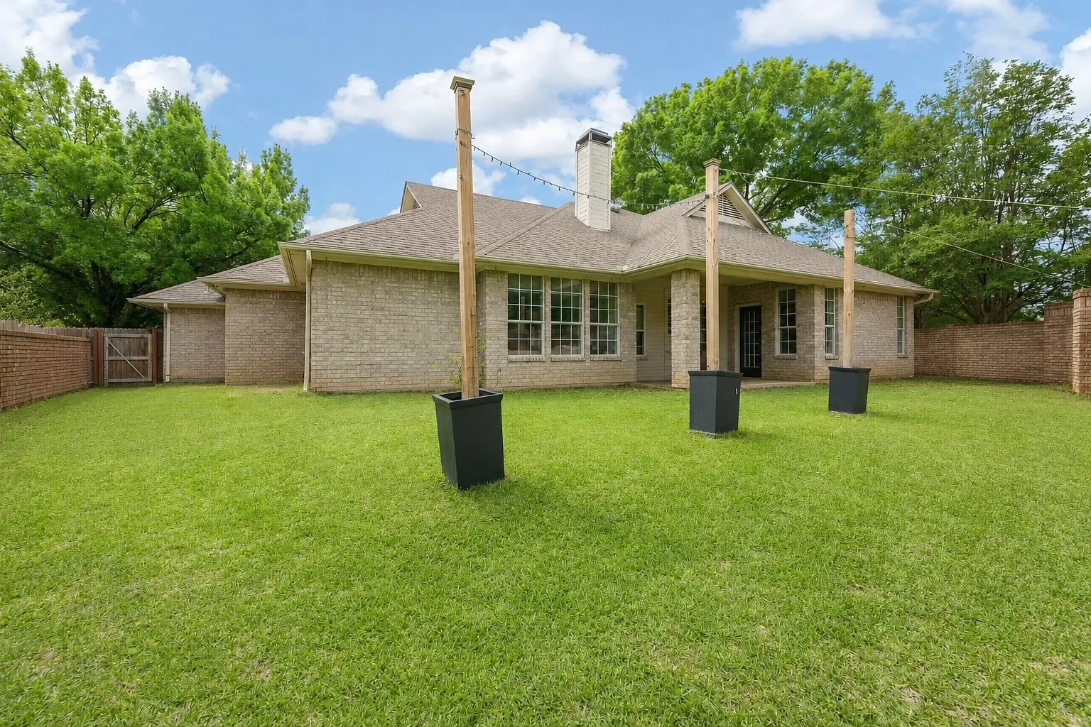 Expansive green lawn surrounds a brick exterior home with a covered patio