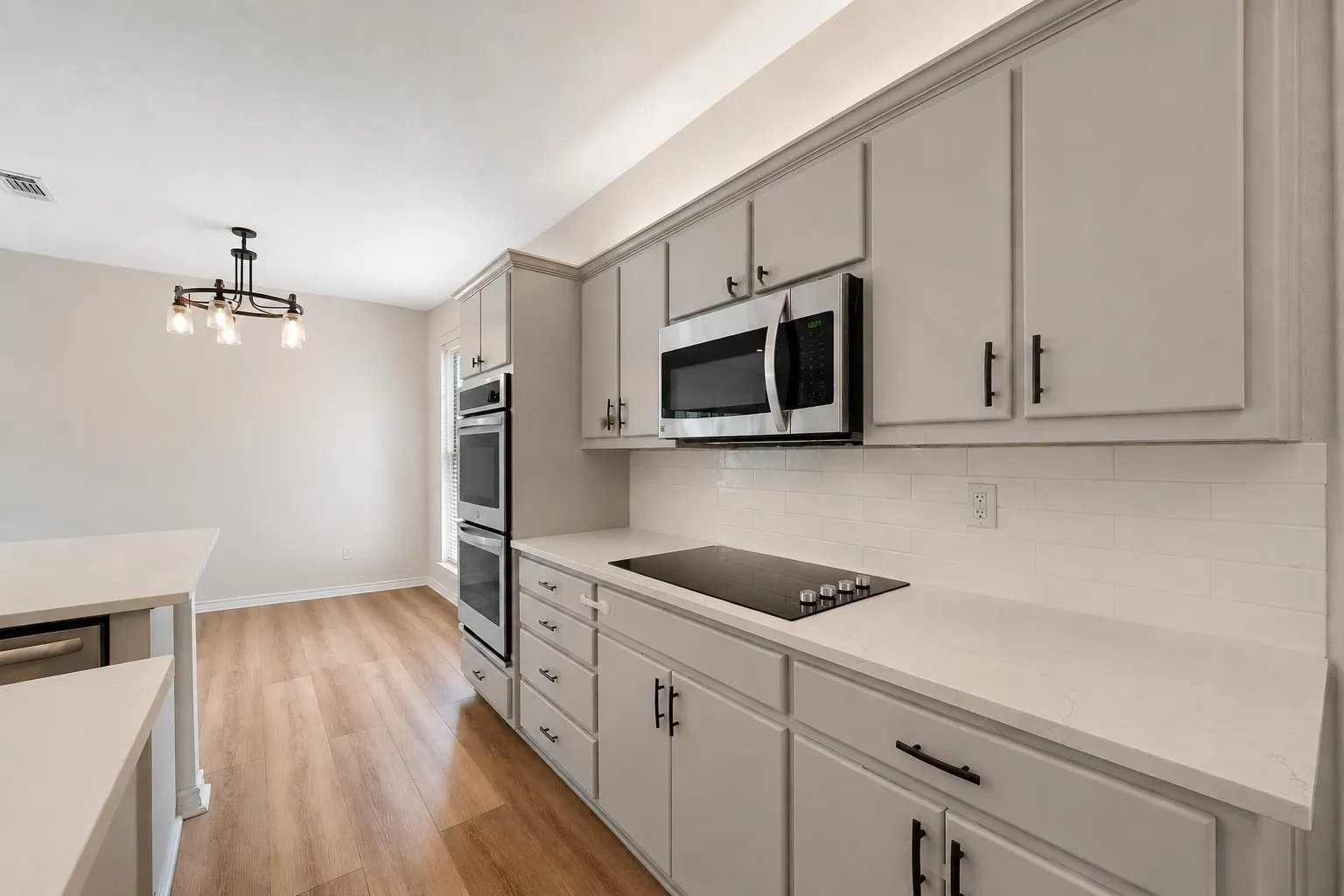 Modern kitchen featuring light-toned cabinetry, light-toned countertops, and wood-finish flooring