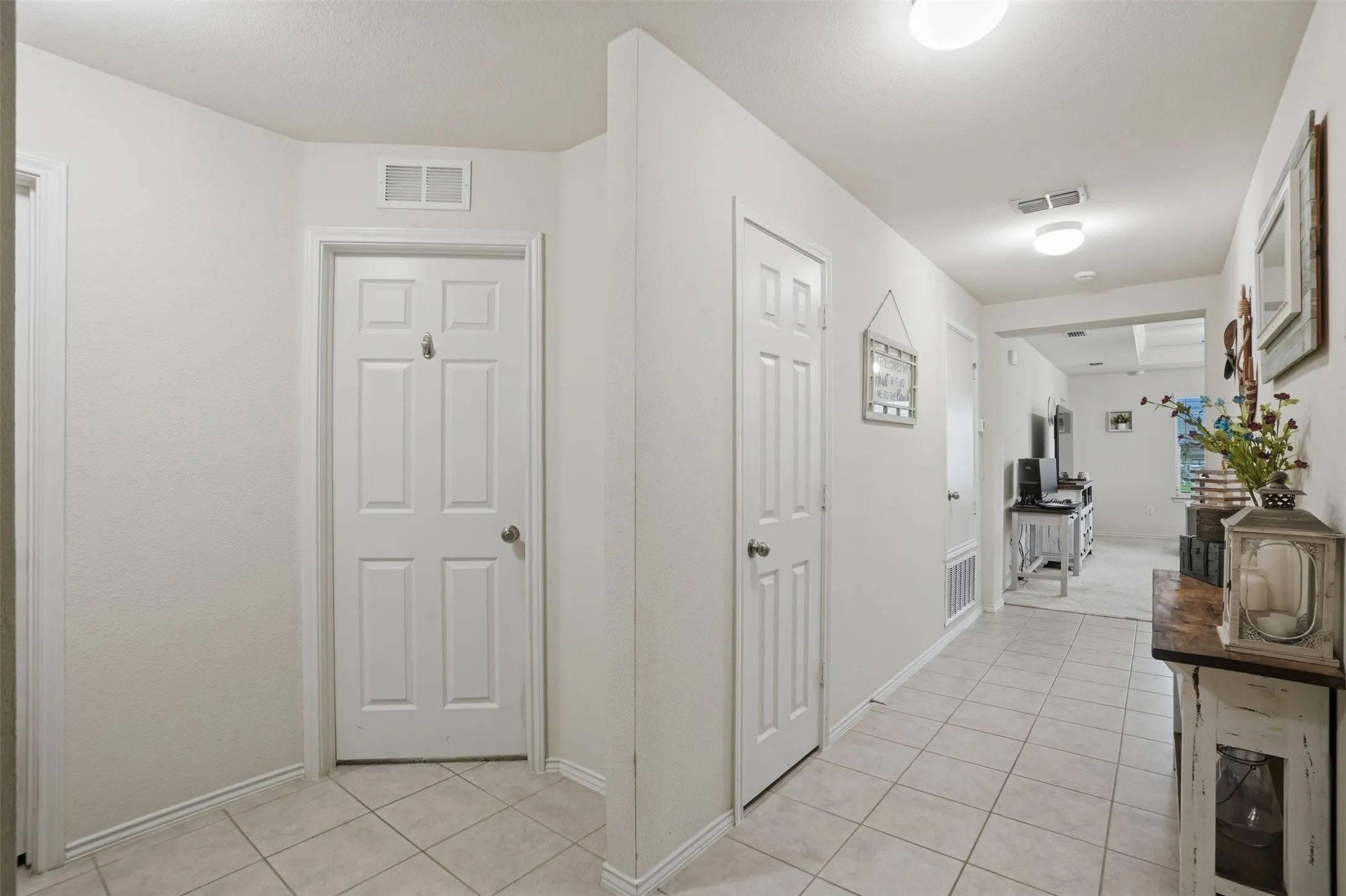 Hallway featuring light-toned tile flooring, white six-panel doors, and recessed ceiling lights