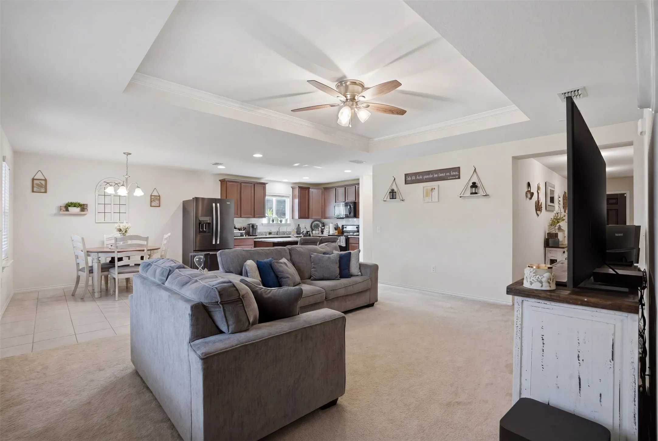 Open-concept living area featuring a tray ceiling with crown molding and a ceiling fan