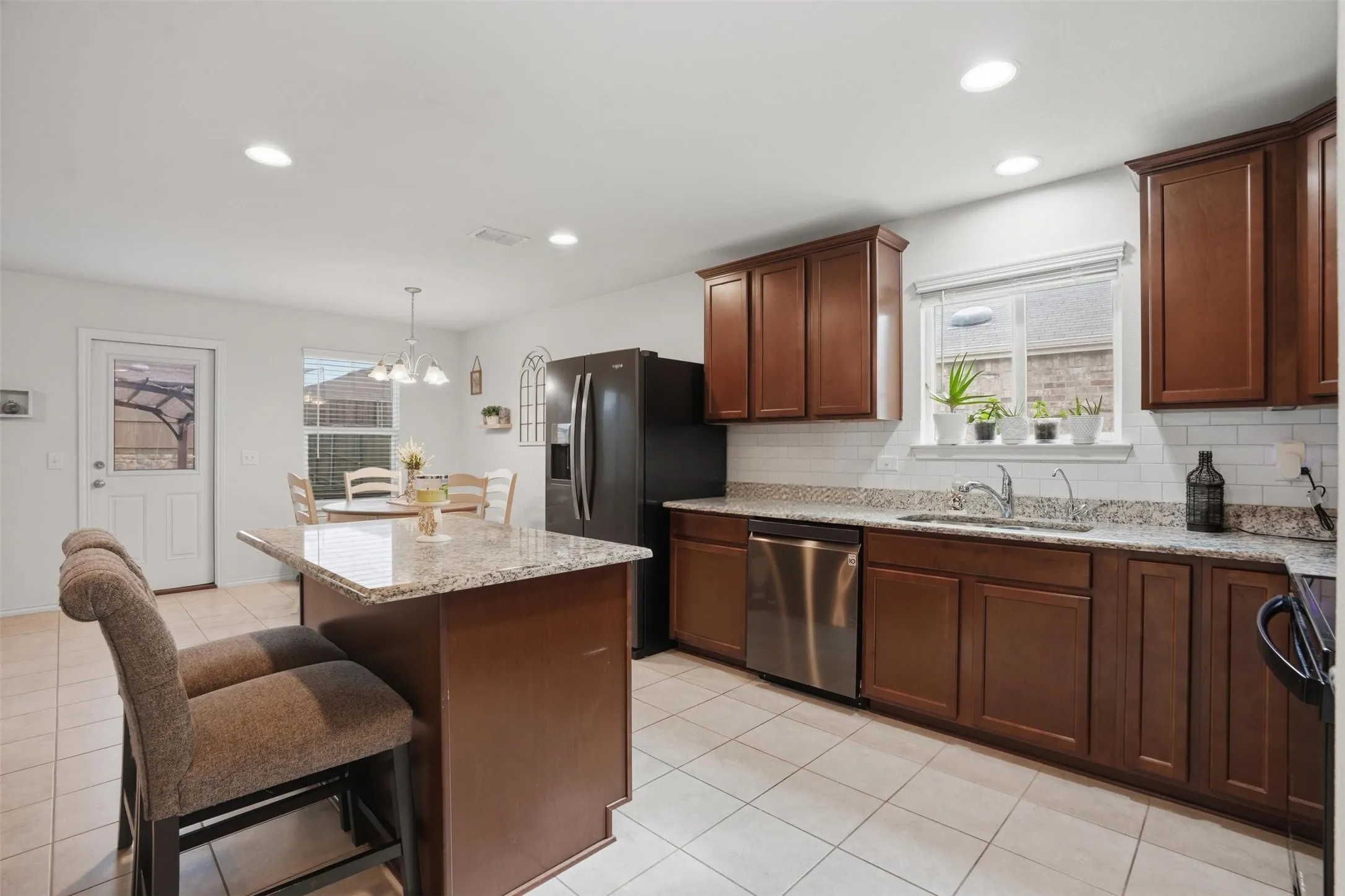 Kitchen featuring a central island, recessed lighting, tile flooring, and a window above the sink