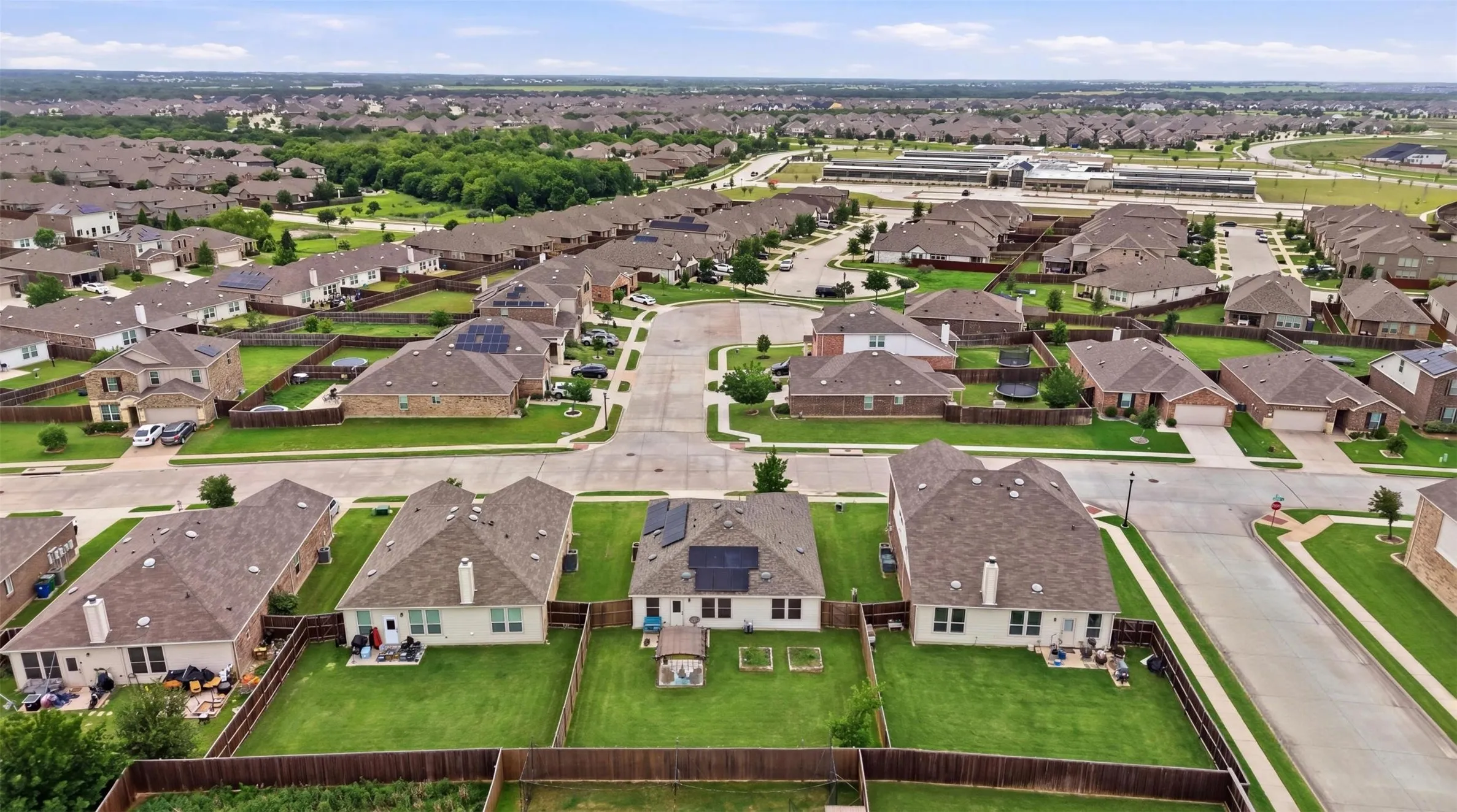 Residential neighborhood featuring single-family homes with fenced backyards, paved streets, and concrete sidewalks