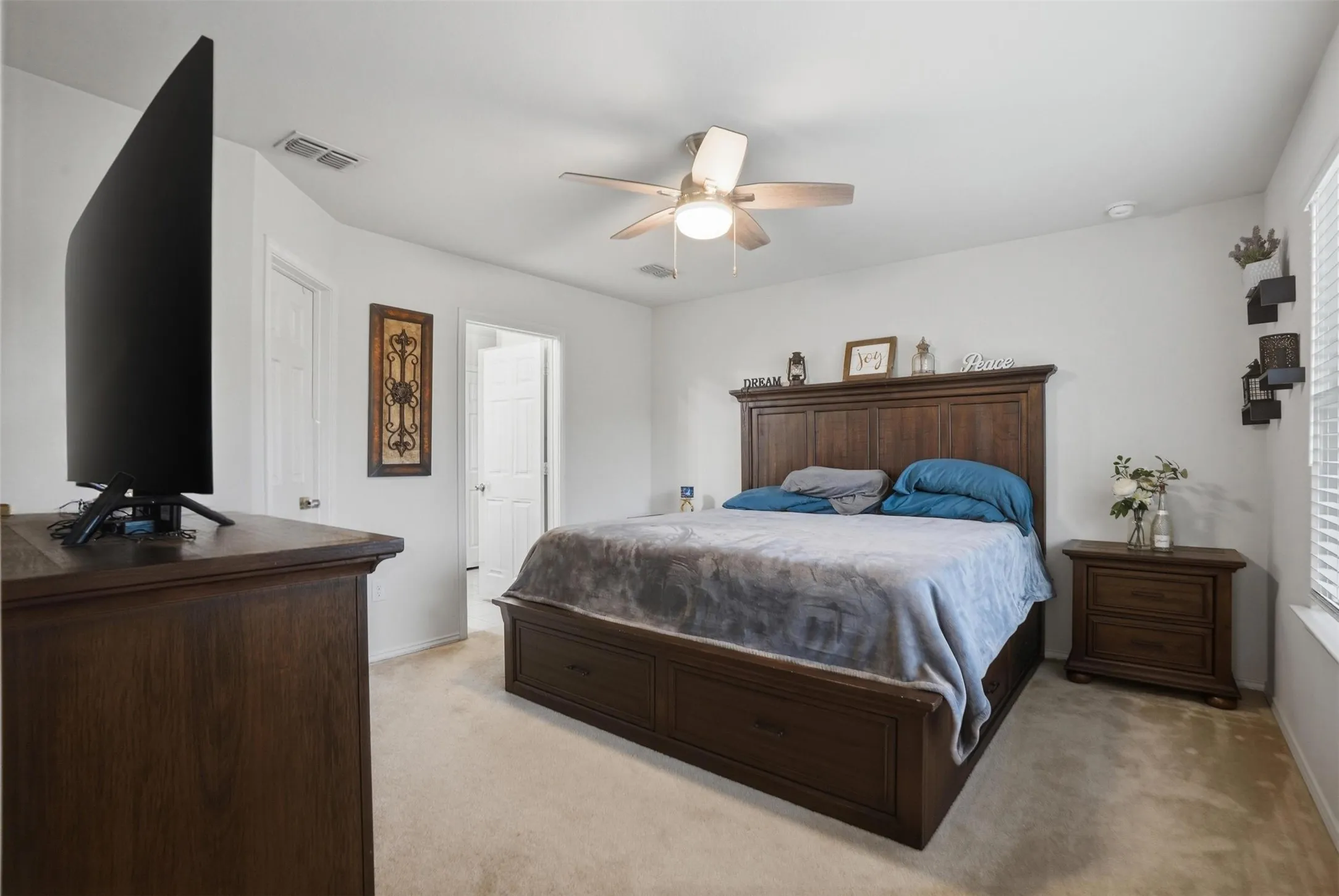 Carpeted bedroom with a dark wood-finish bed frame, matching dresser, and nightstand