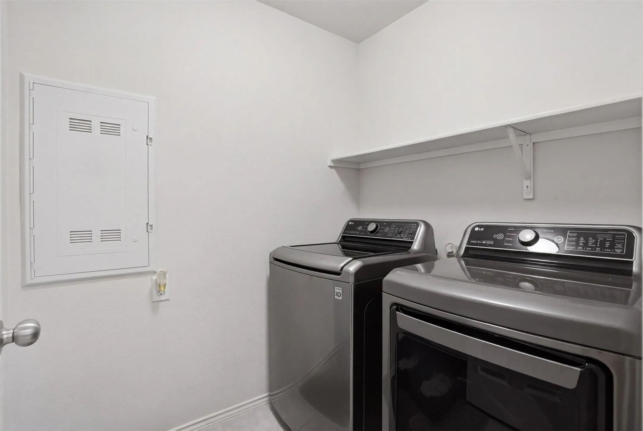 Dedicated utility space featuring a wall-mounted shelving unit and a white electrical panel