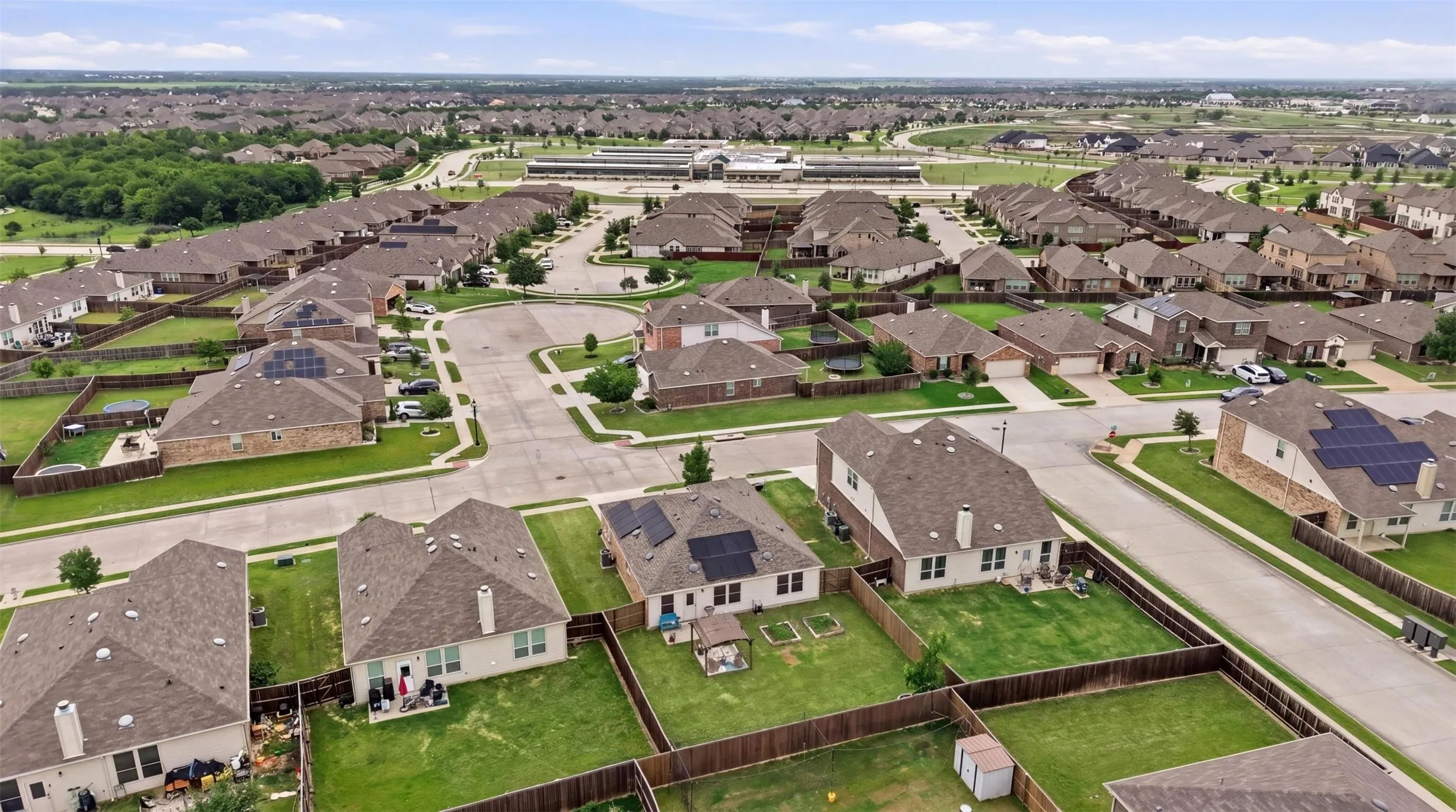 Residential neighborhood featuring single-family homes with pitched shingle roofs and fenced backyards