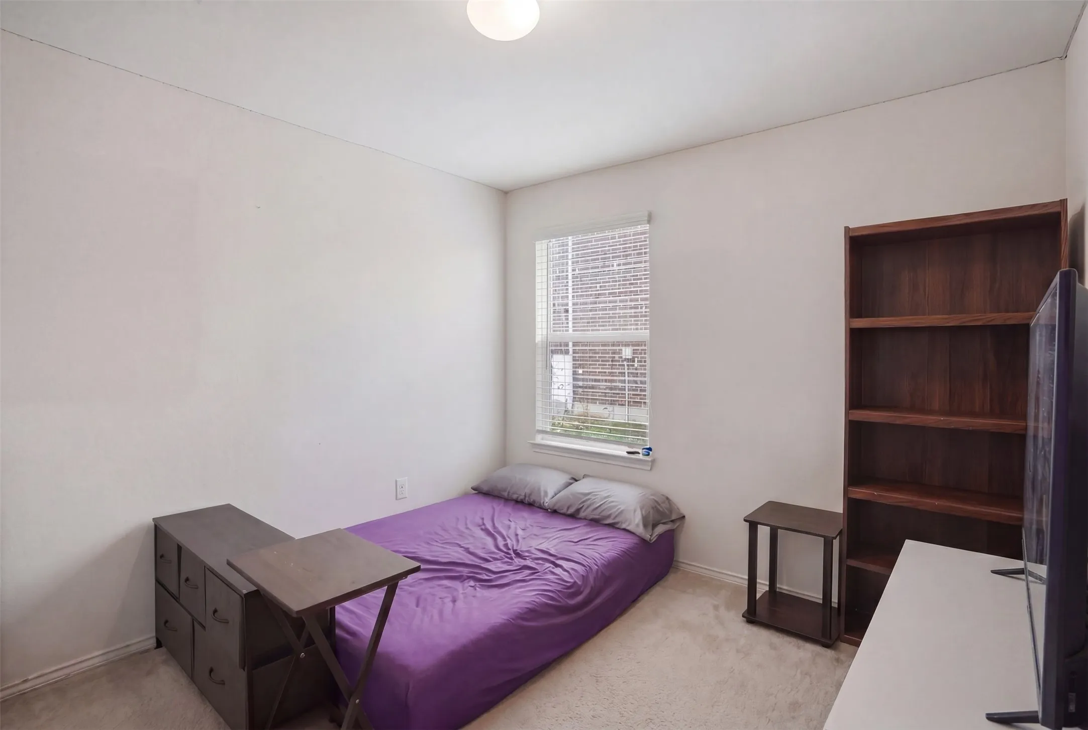 Carpeted room featuring a single window with blinds, white walls, and a ceiling light fixture