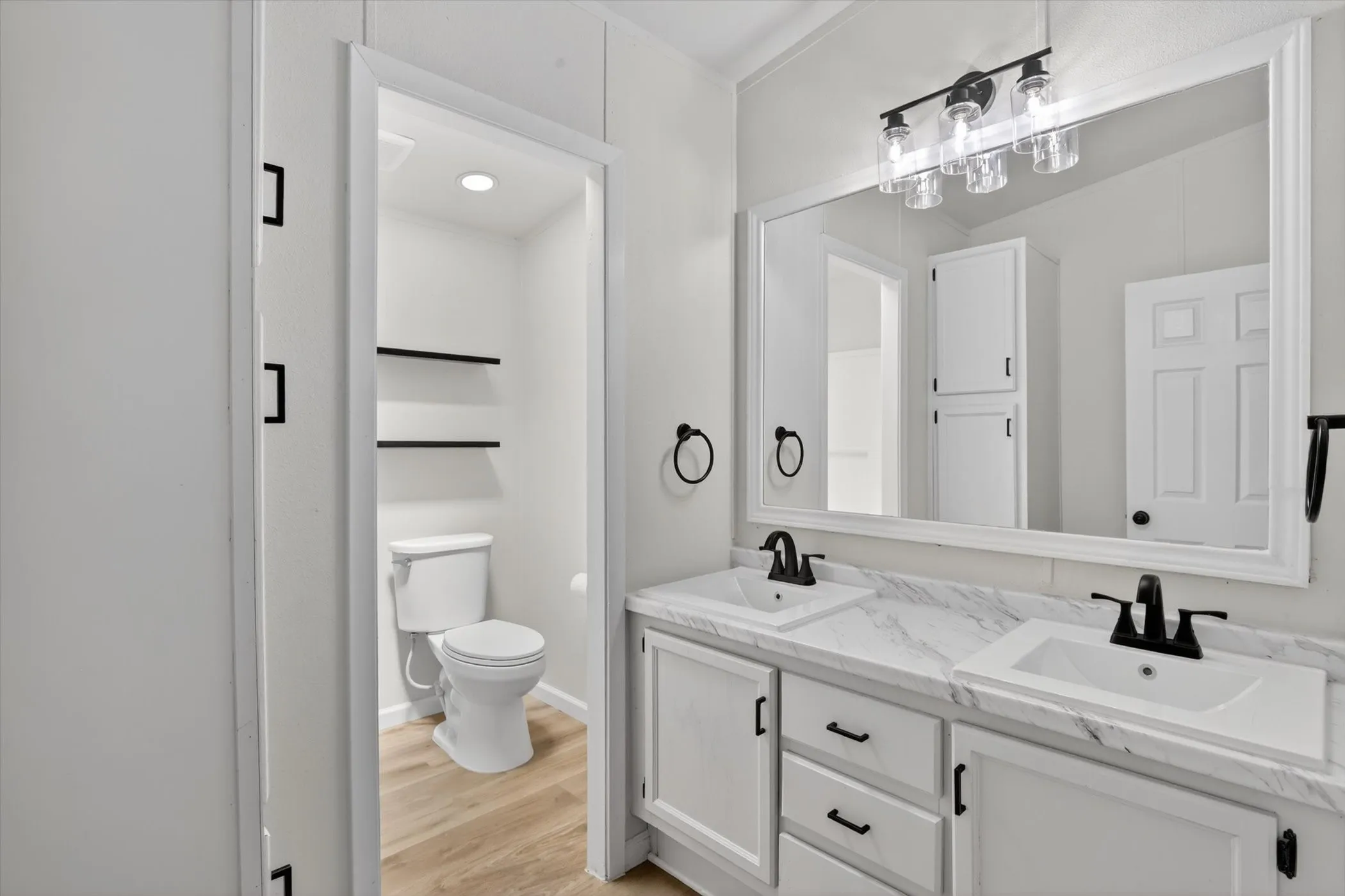 Dual sink vanity featuring white cabinetry, stone-finish countertops, and matte black fixtures