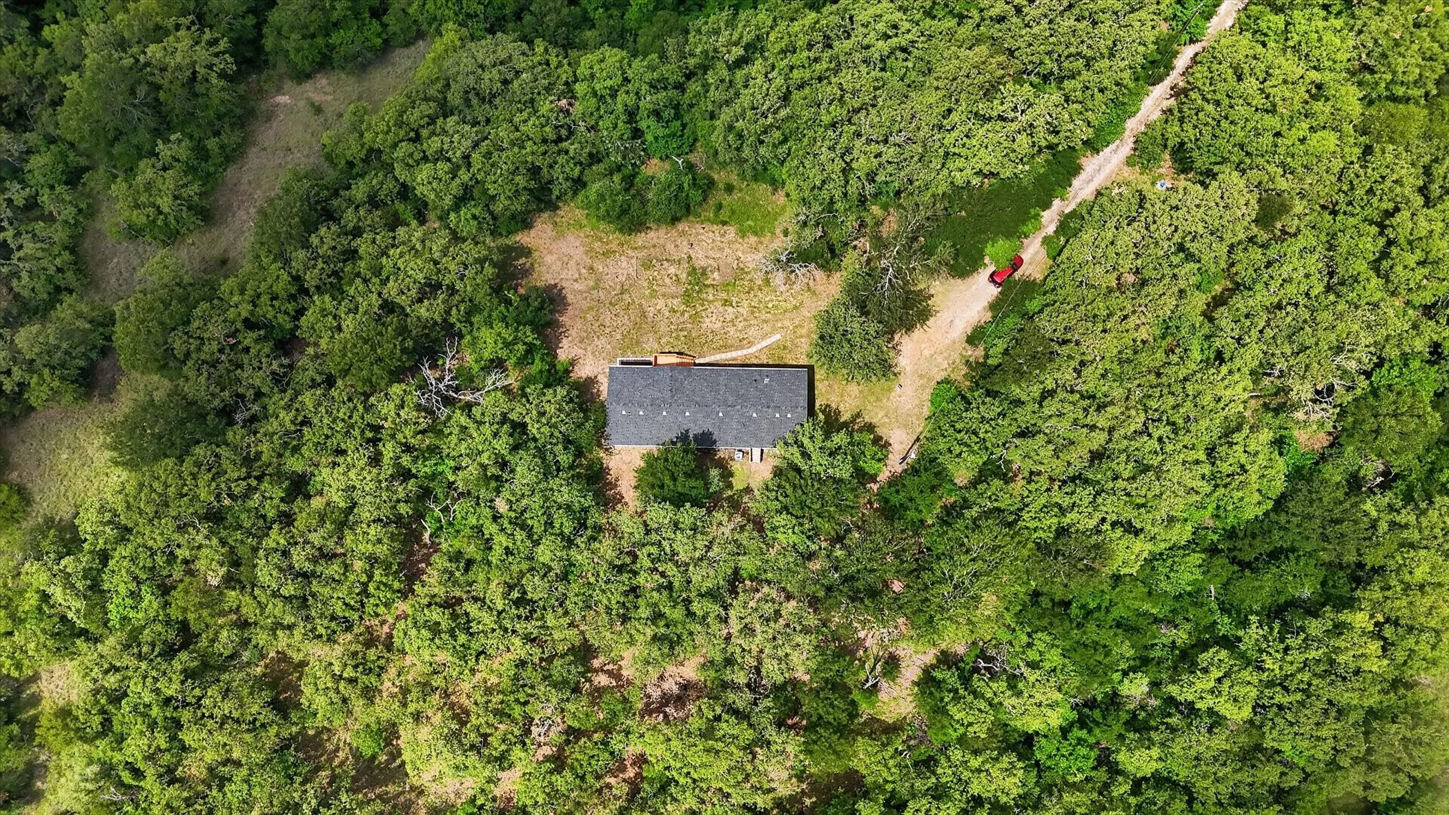Expansive tree-covered landscape featuring a single-story residence with a brown roof, surrounded by mature trees