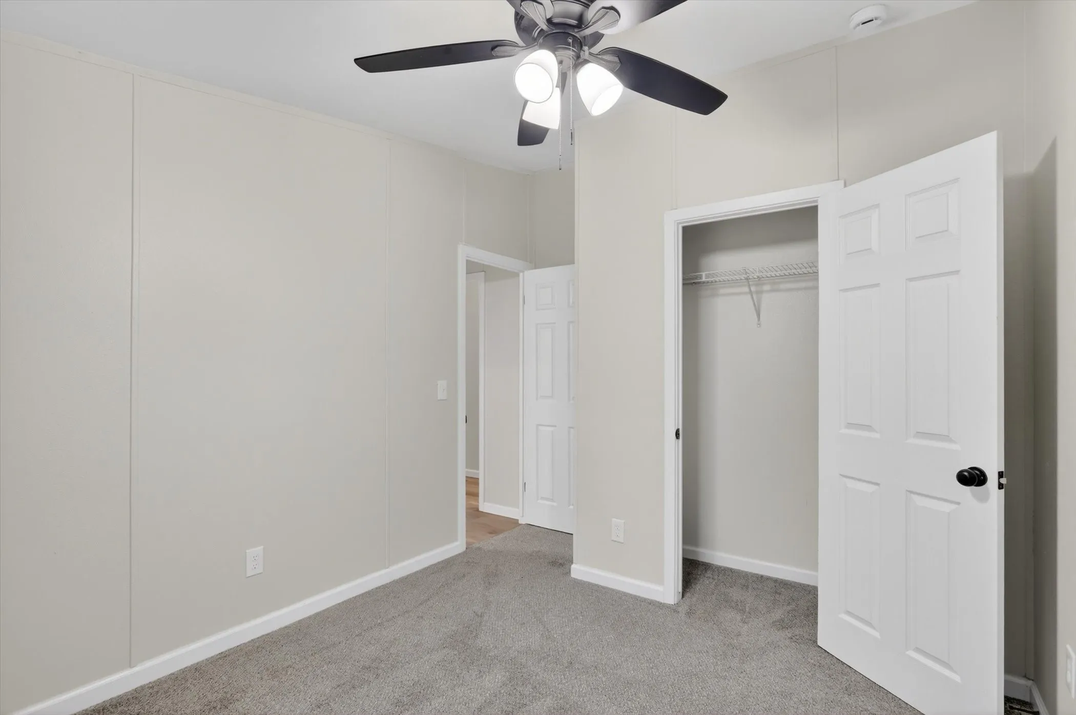Spacious room with grey carpet flooring and light grey wall paneling
