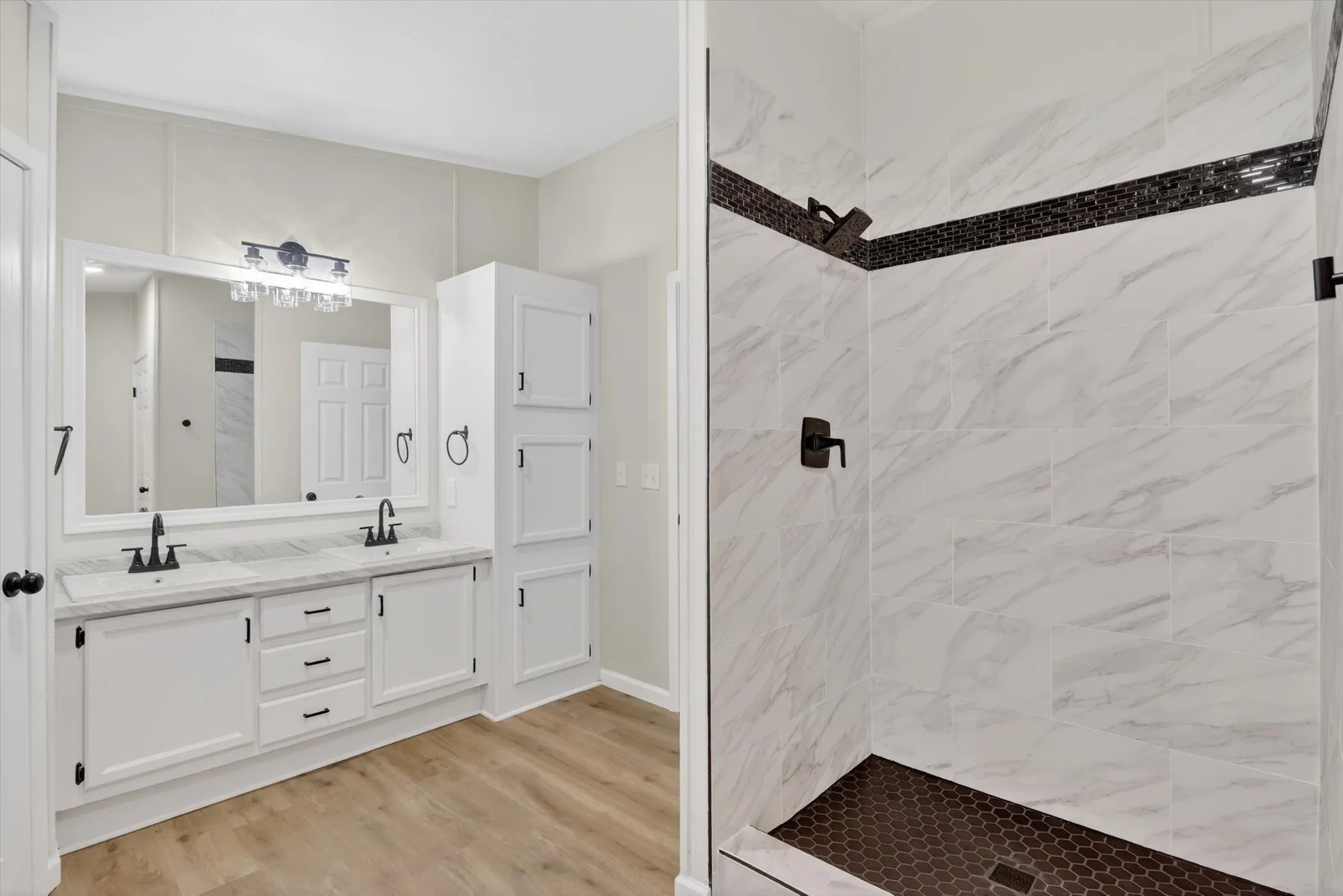Dual sink vanity with white cabinetry, black hardware, and an expansive mirror