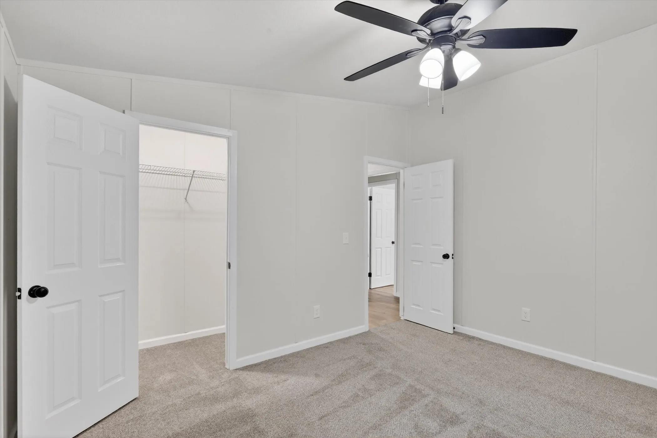 Neutral-toned wall paneling with a ceiling fan featuring a dark finish and integrated lighting