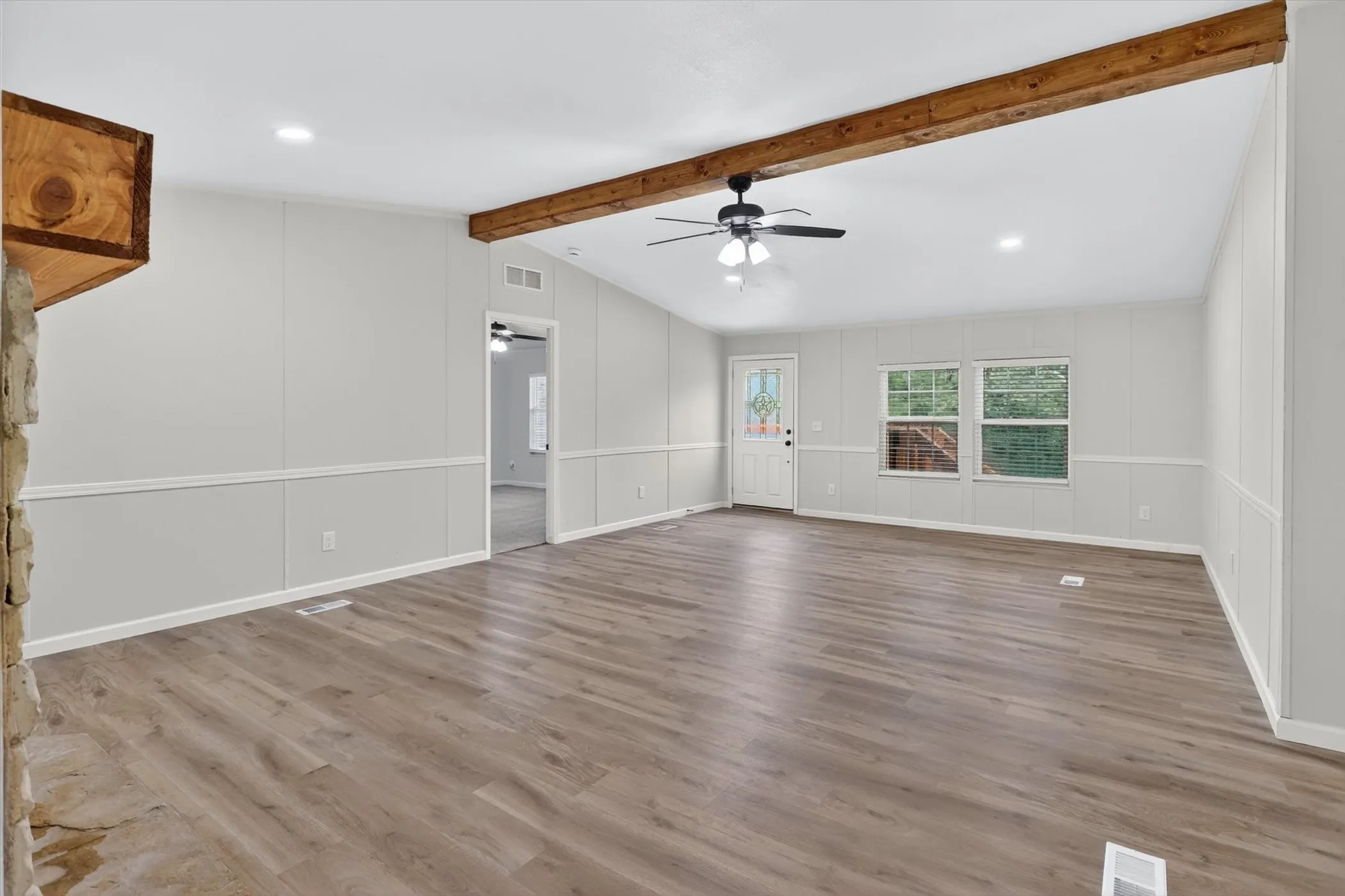 Spacious living area featuring wood-finish flooring and a vaulted ceiling with exposed wood beams