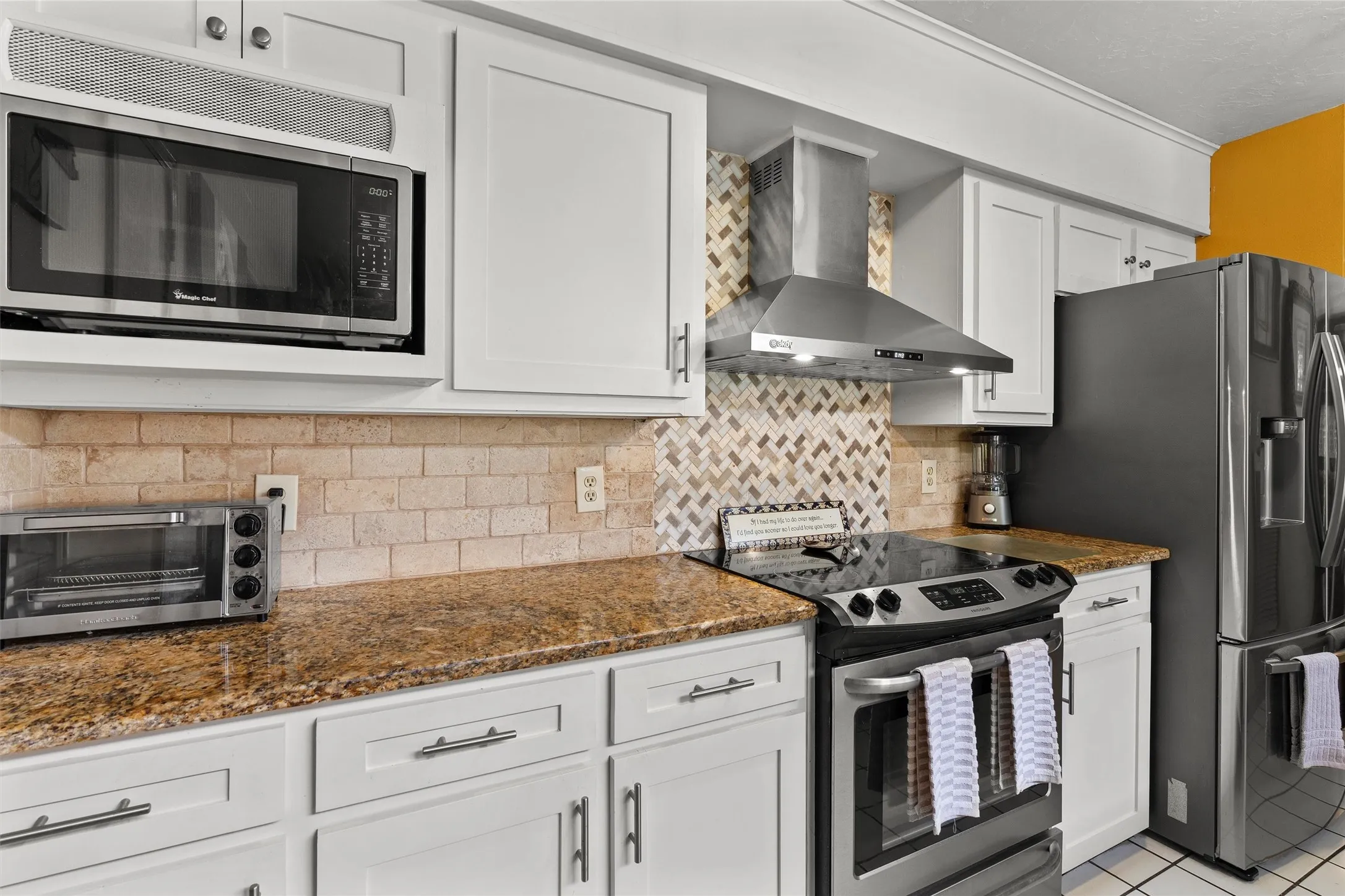 Kitchen featuring white cabinetry, granite-finish countertops, stainless steel appliances, and a tiled backsplash