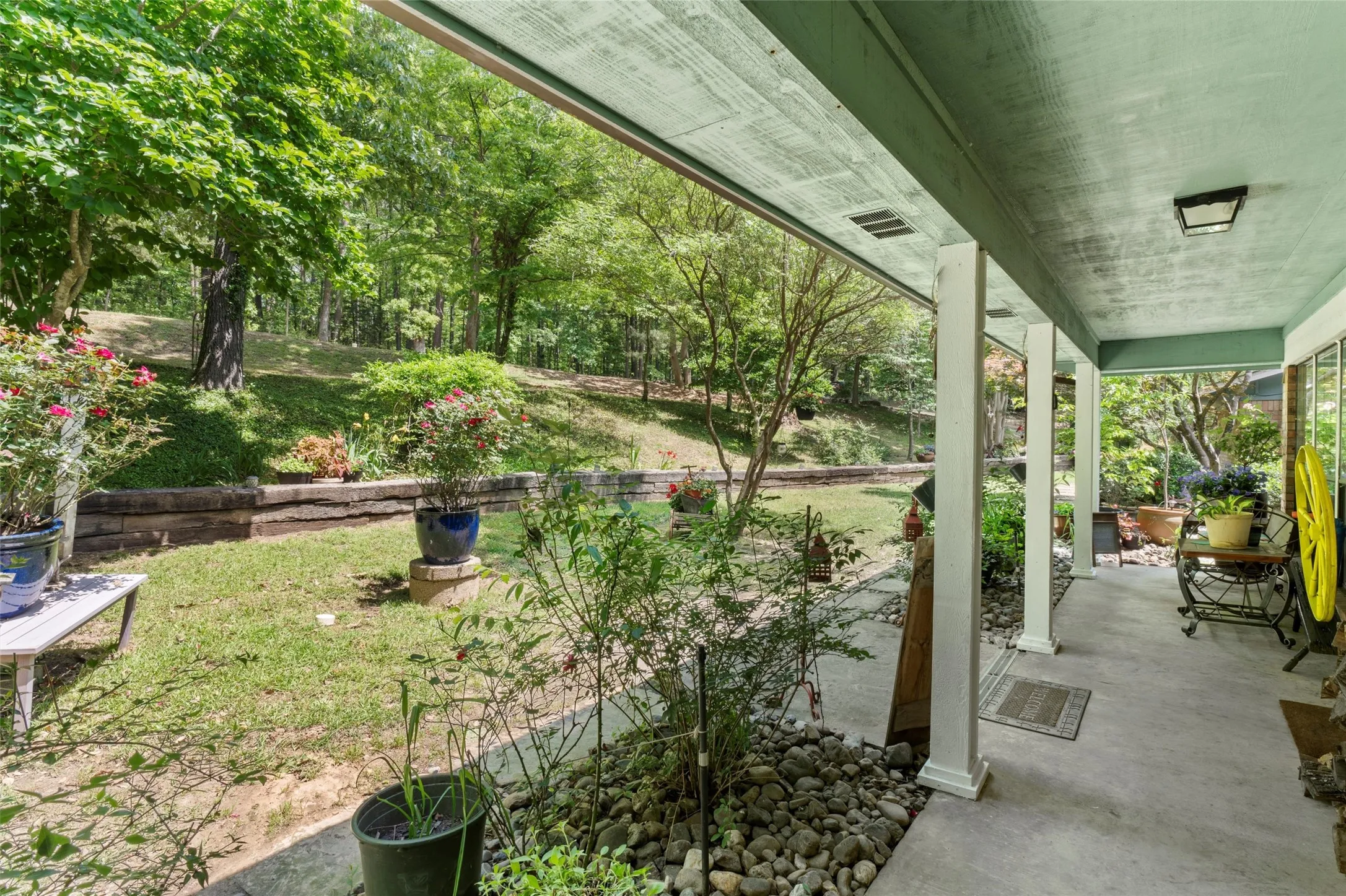 Covered porch with square white columns, concrete flooring, and an overhead light fixture