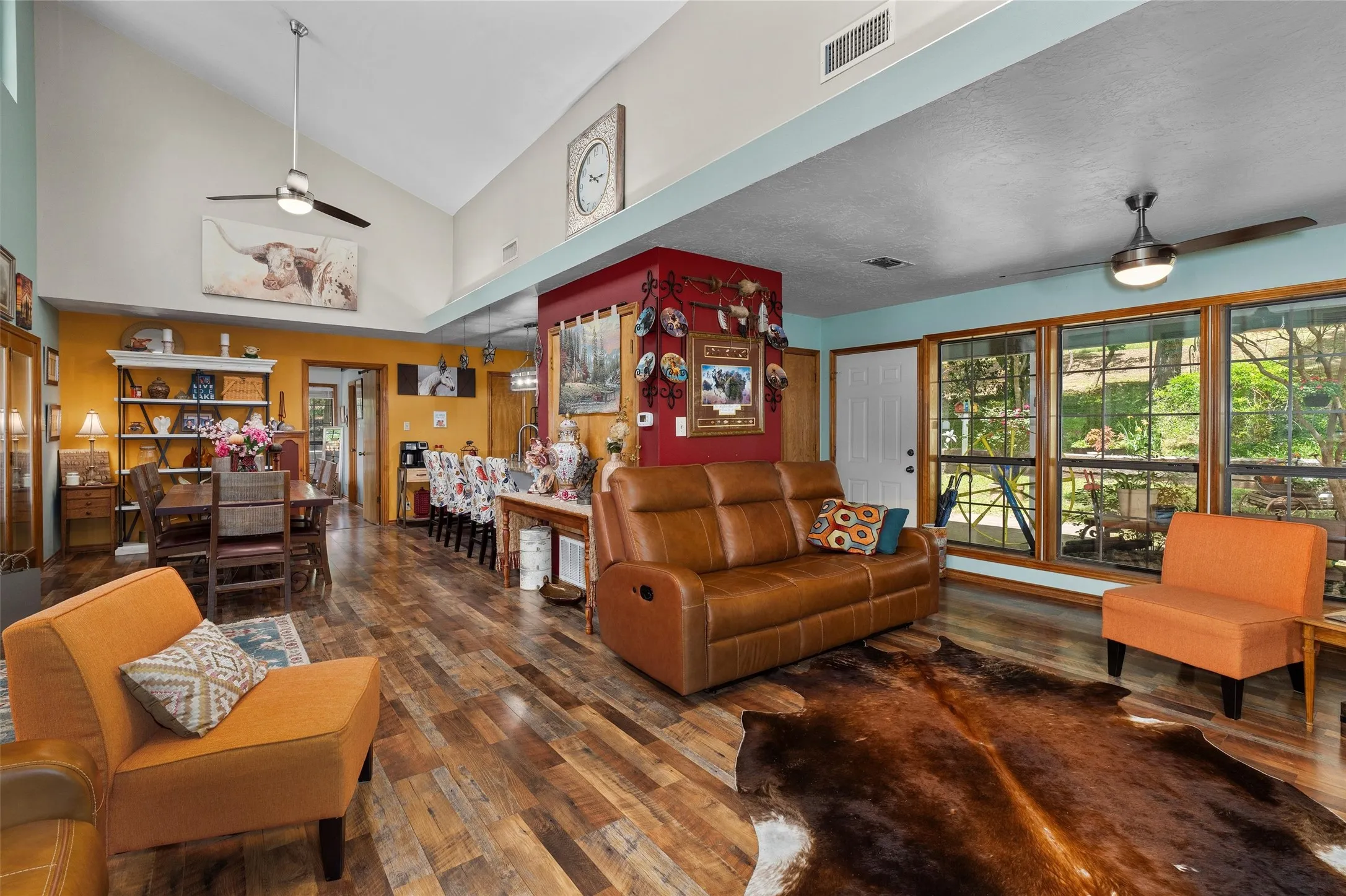 Spacious living area featuring vaulted ceilings, wood-finish flooring, and ample natural light through multiple windows