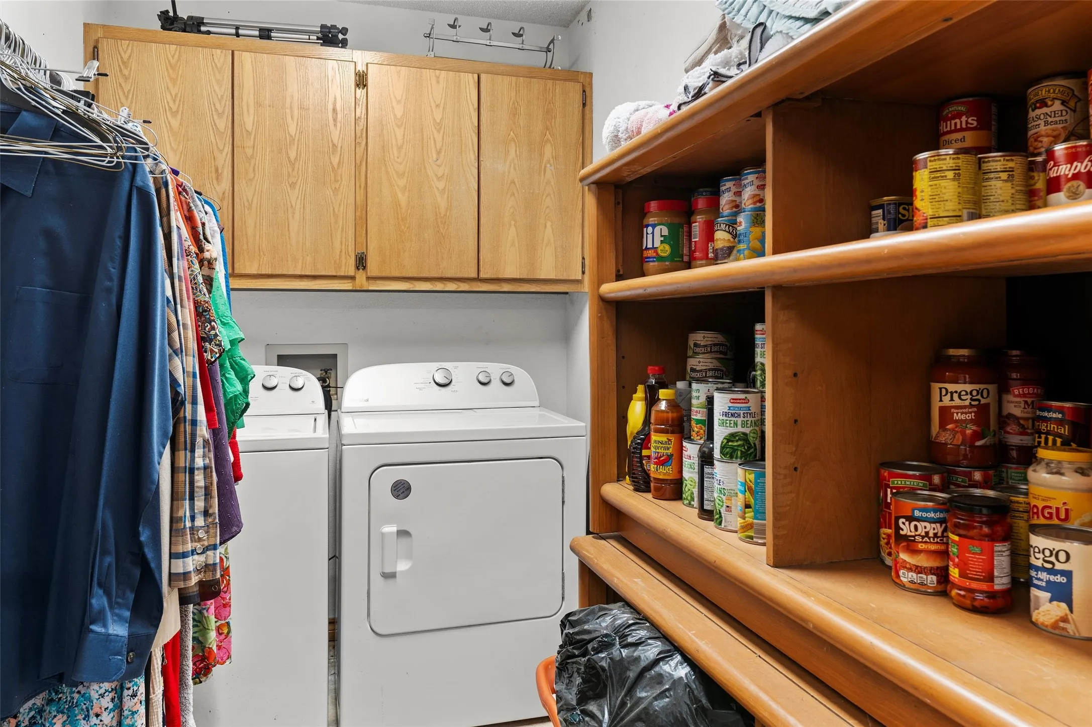 Laundry area featuring a side-by-side washer and dryer, wood cabinetry, and a clothes hanging rod