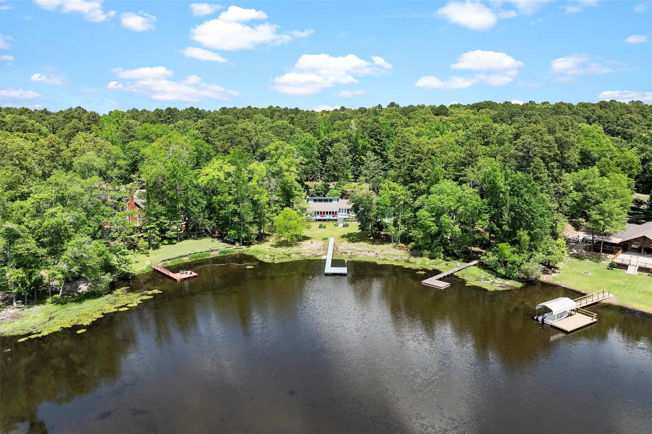 Lakefront property featuring a private dock, expansive green space, and mature trees