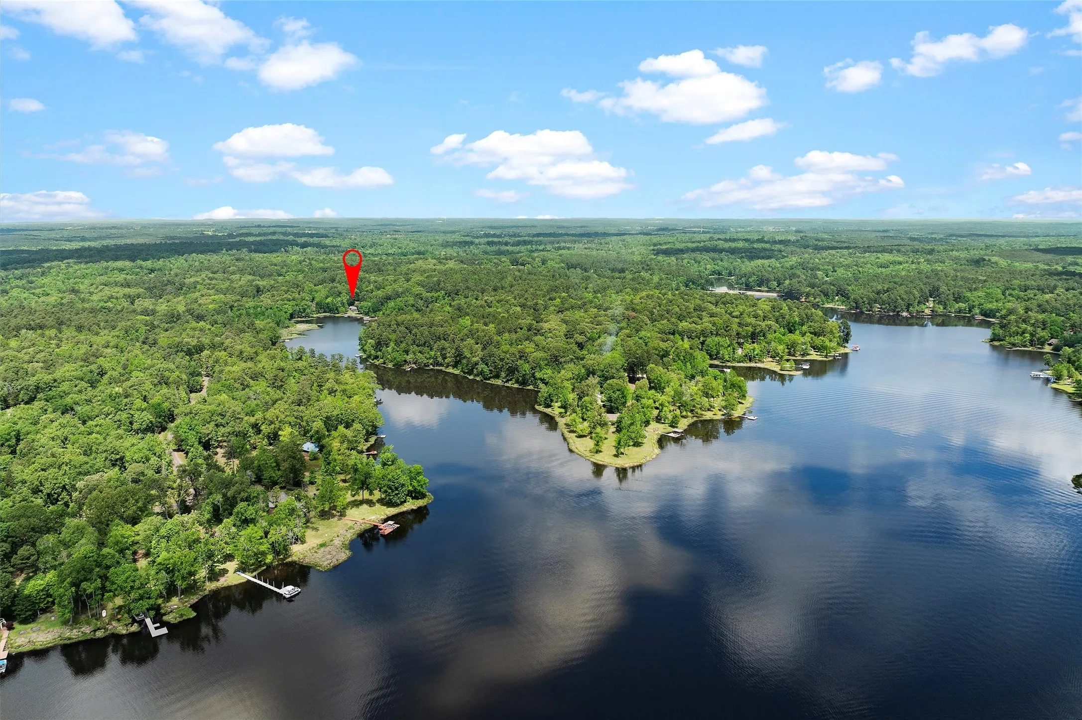 Expansive waterfront property situated on a wooded lot, featuring a private dock and direct lake access