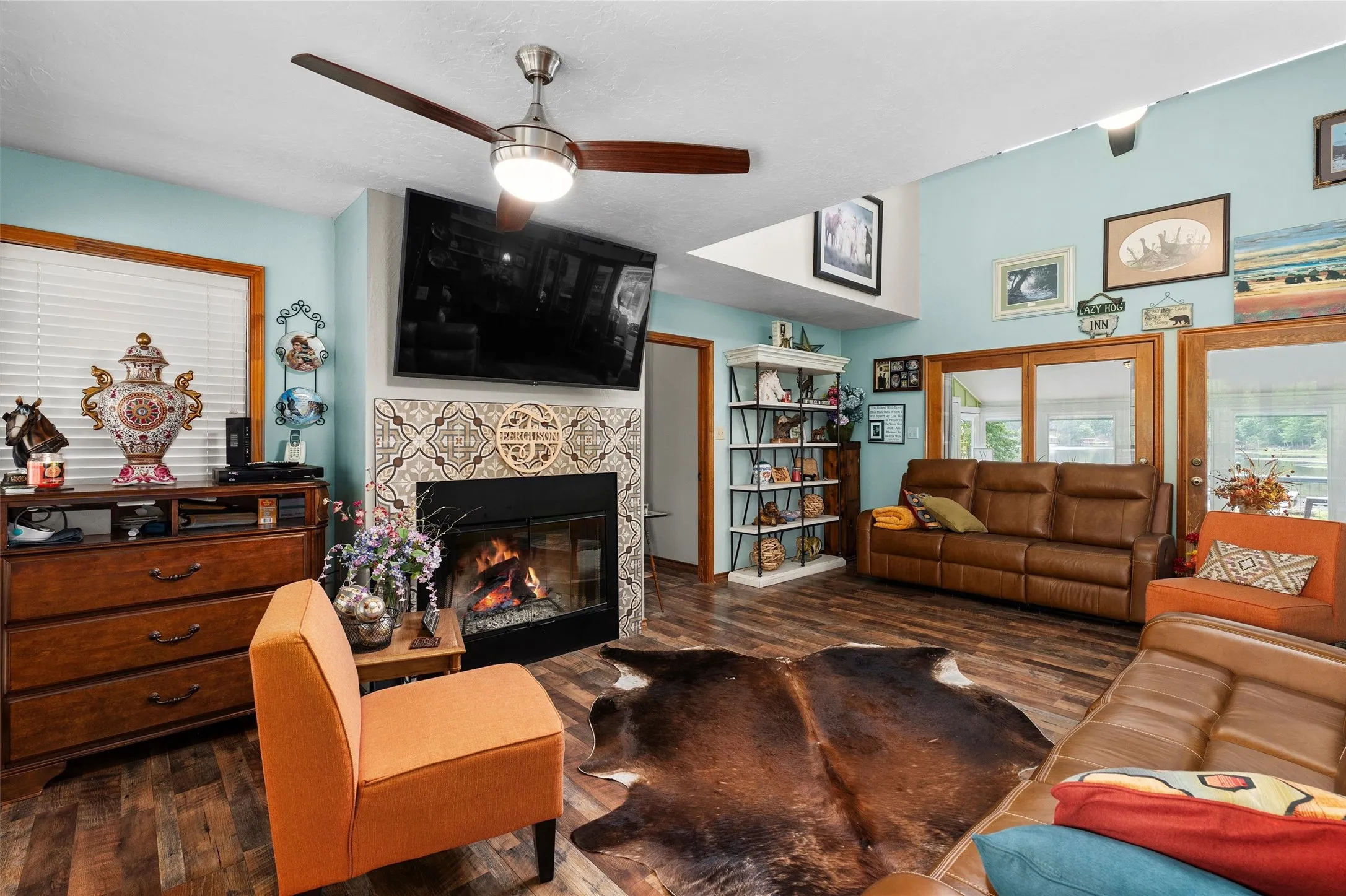 Living area featuring wood-finish flooring, a fireplace with decorative tile surround, and vaulted ceilings