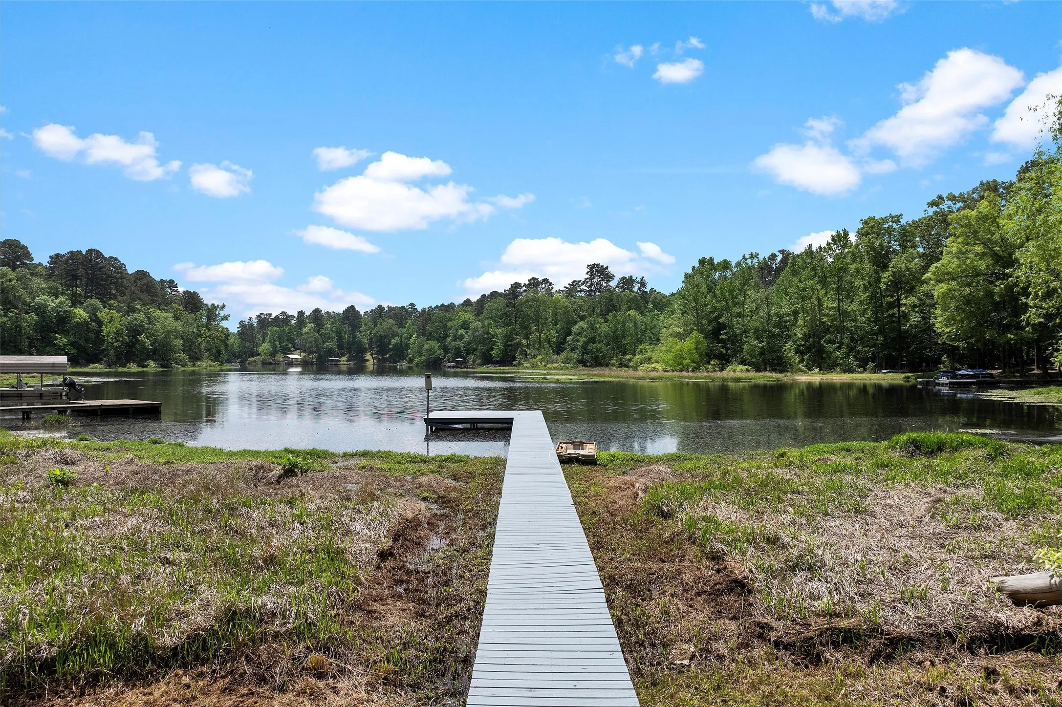 Private dock extending into a serene lake, surrounded by lush, mature trees