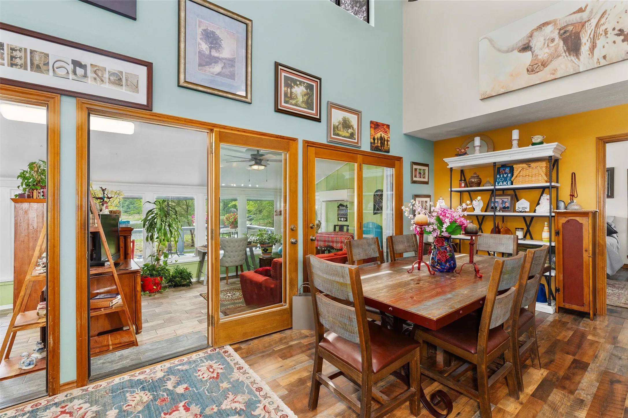 Dining area featuring wood-finish flooring, a vaulted ceiling, and sliding glass doors opening to a sunroom