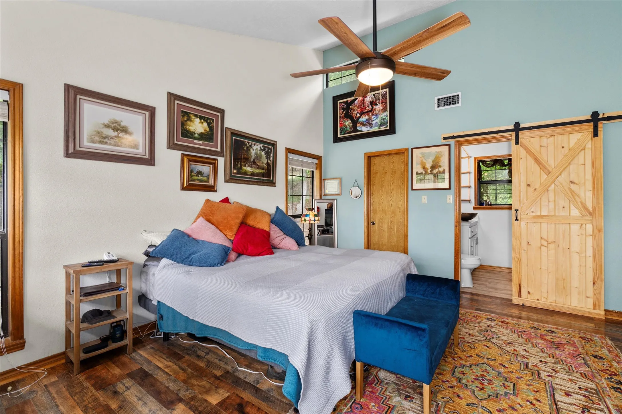Vaulted ceiling room featuring wood-finish flooring and a wood-paneled barn door