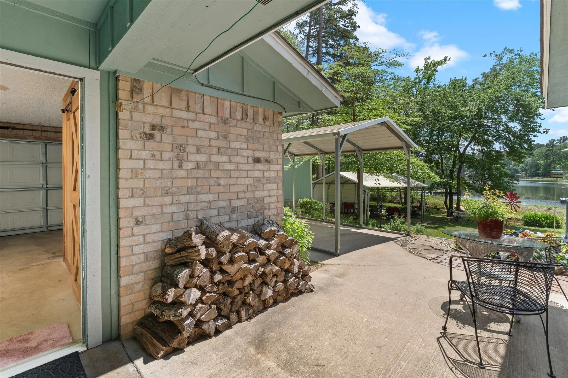 Exterior patio featuring a concrete surface, a brick wall, and a wood-finish barn door