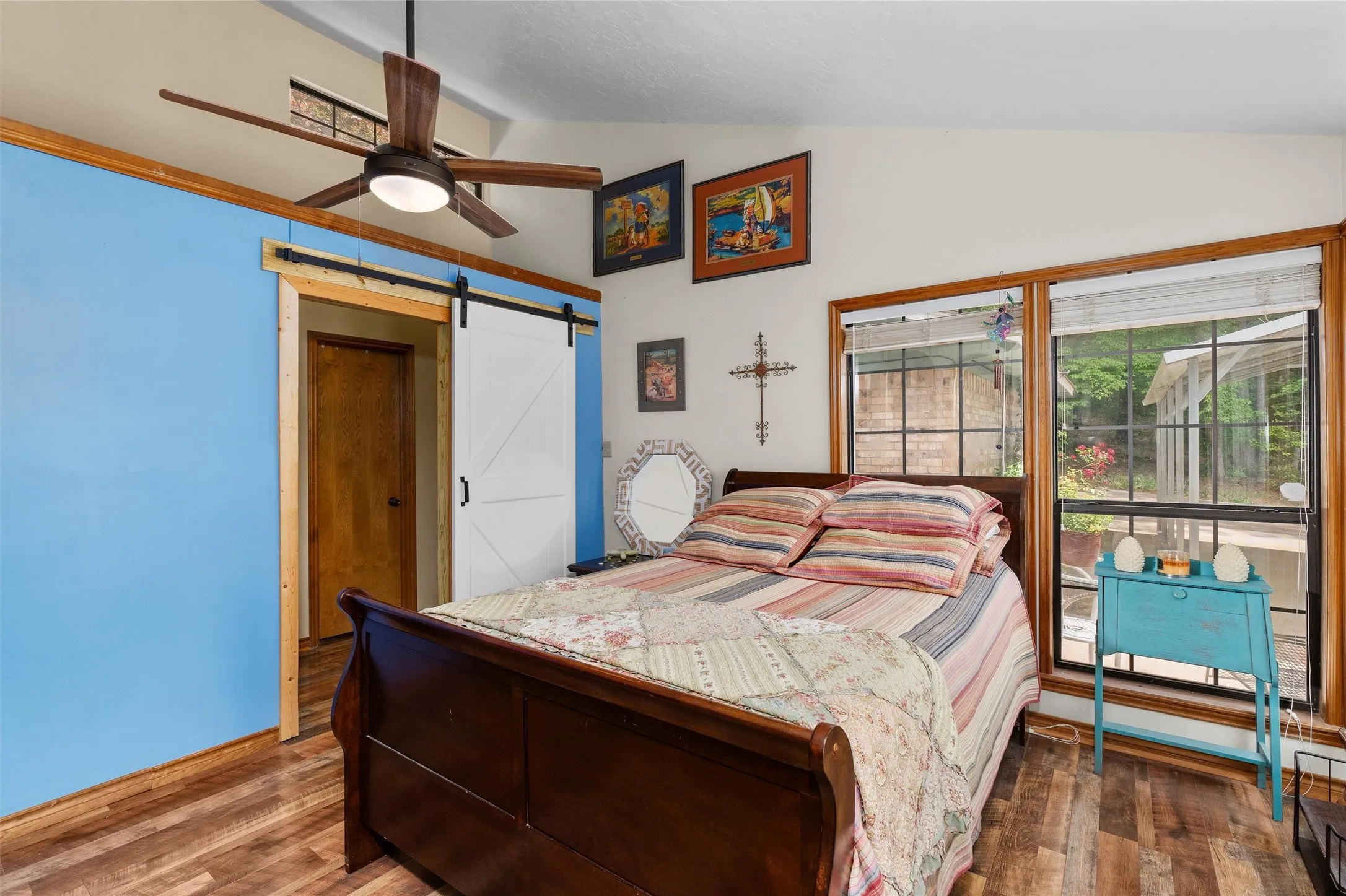 Spacious interior featuring wood-finish flooring, a contemporary ceiling fan, and large windows with natural wood trim
