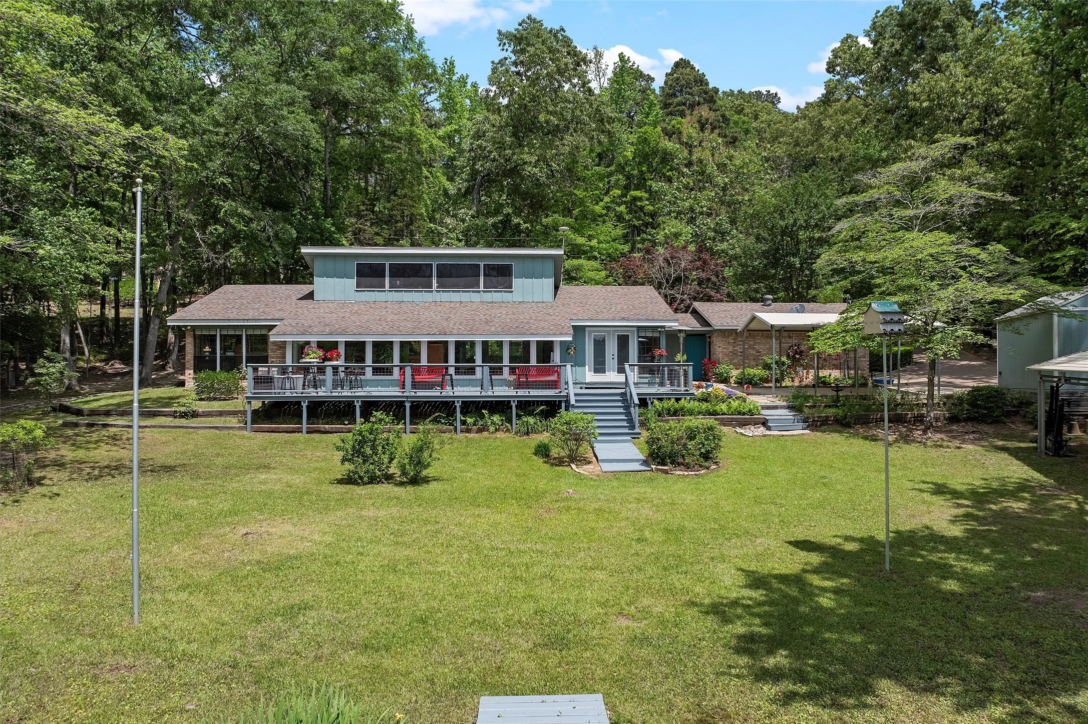 Expansive lawn area with a multi-level deck and stairs leading to the main entrance