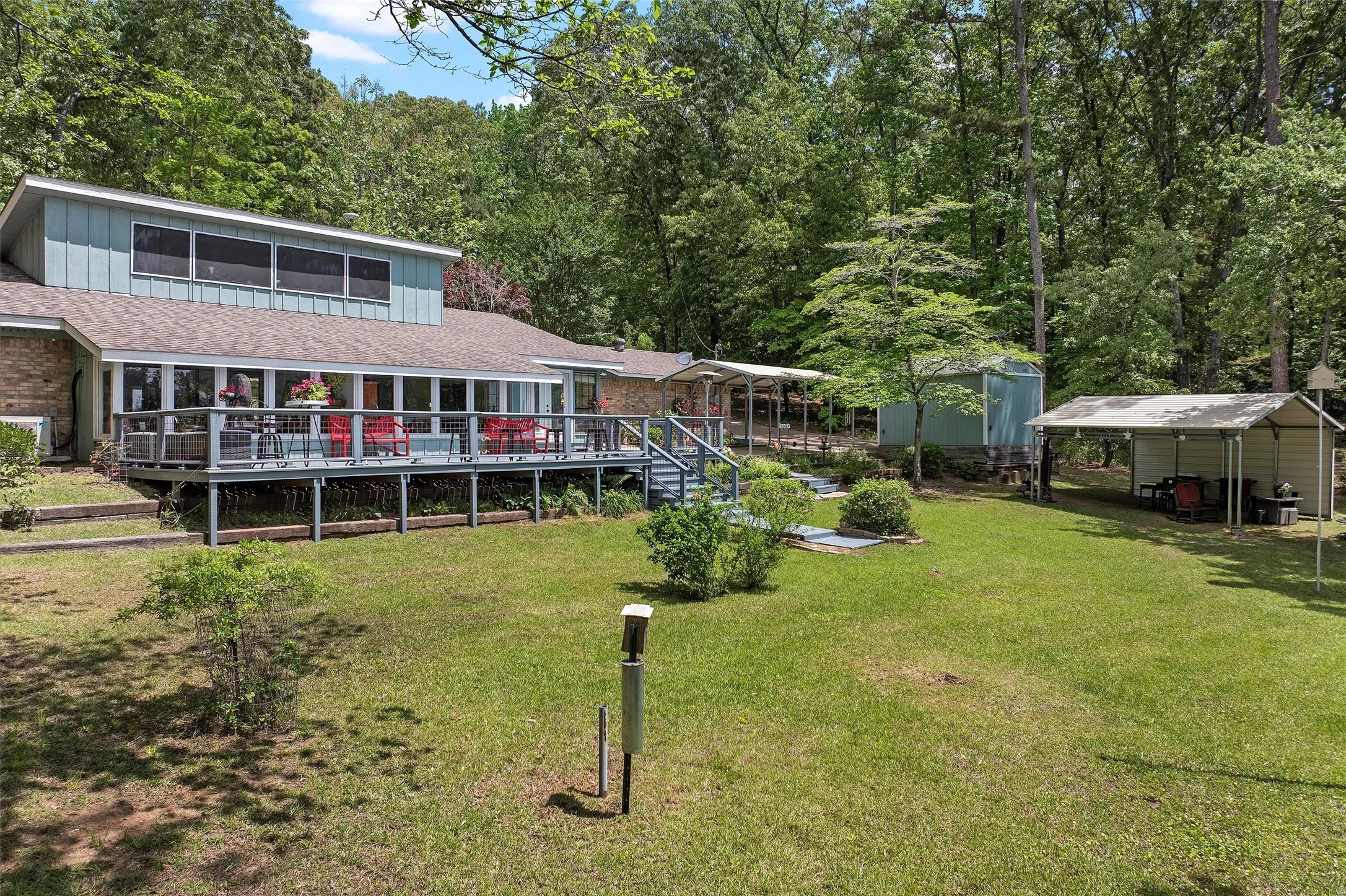 Expansive backyard featuring a lush lawn, mature trees, and multiple outbuildings