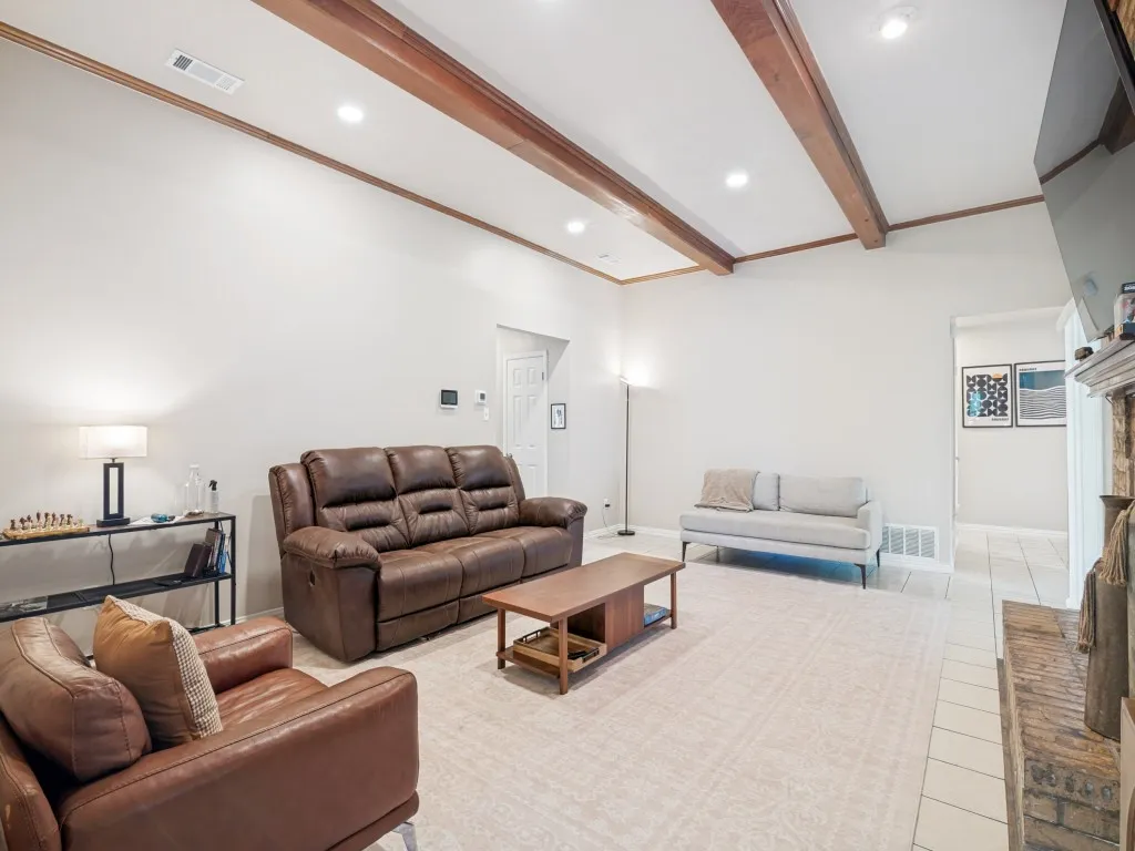 Spacious living area featuring exposed wood ceiling beams and recessed lighting