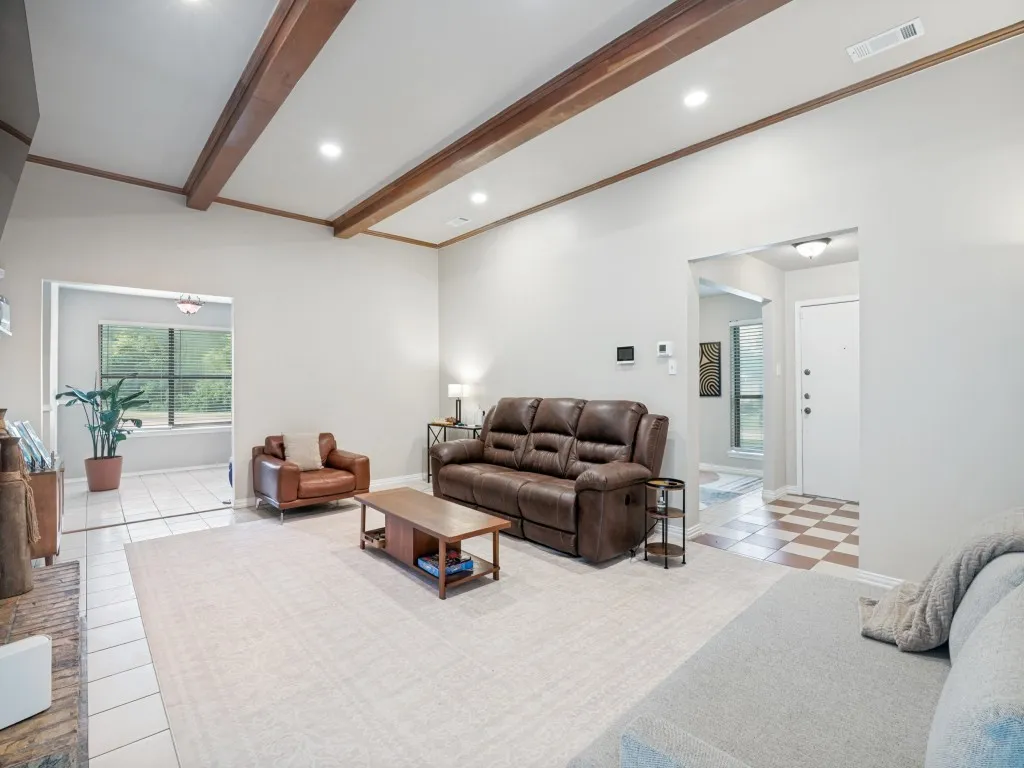 Spacious living area featuring exposed wood beam ceiling accents and recessed lighting