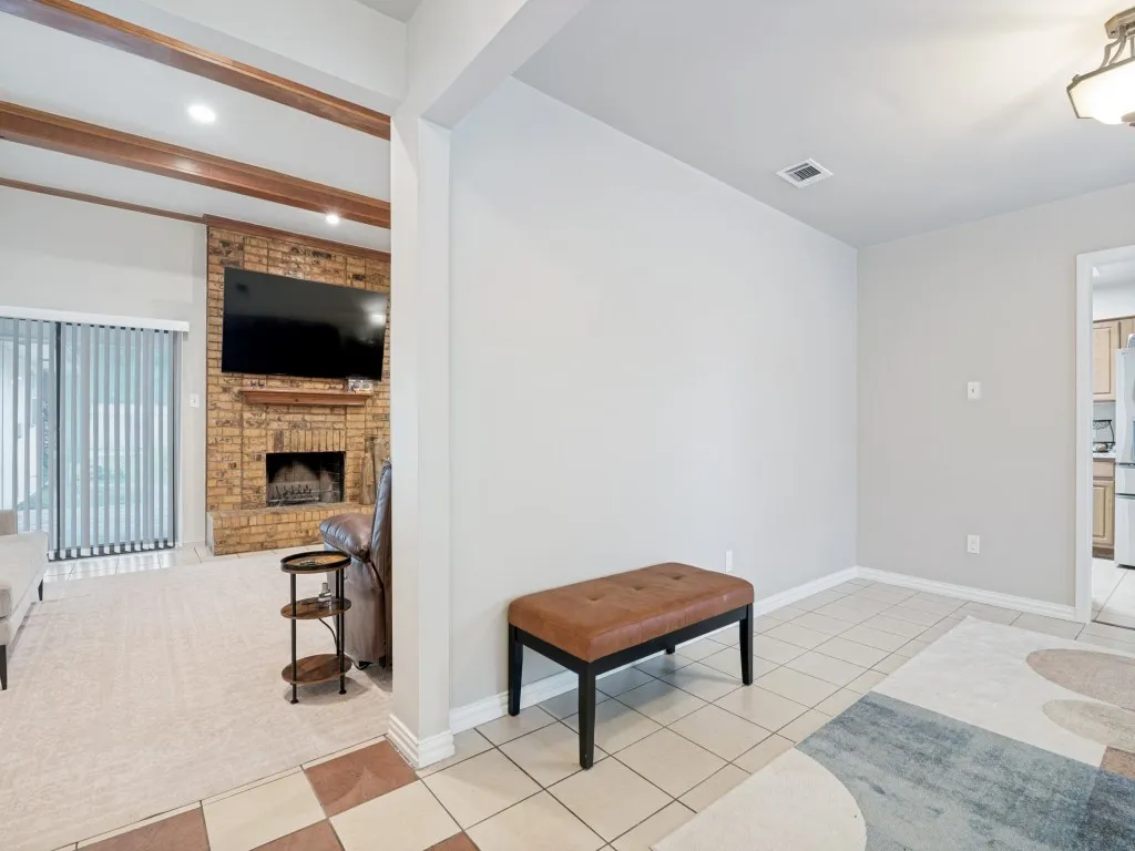 Living room featuring a brick fireplace, wood mantel, and wood-finish ceiling beams