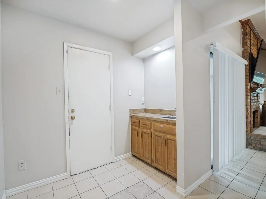 Utility area featuring wood cabinetry, stone-finish countertop, and a built-in sink