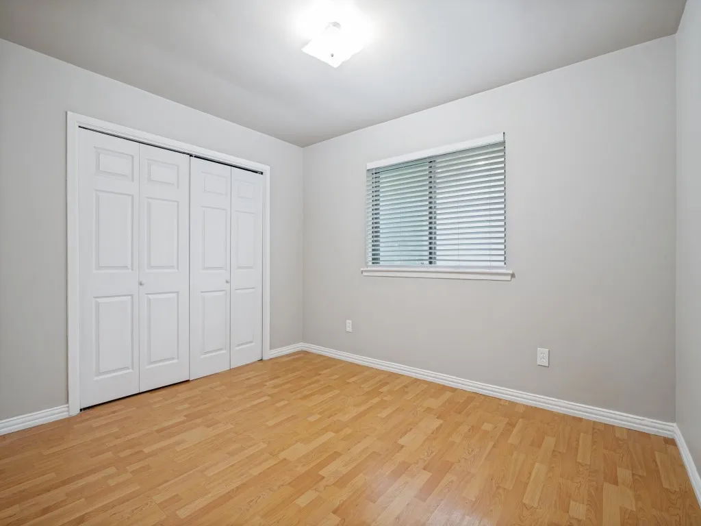 Spacious room with wood-finish flooring, light gray walls, and white baseboards