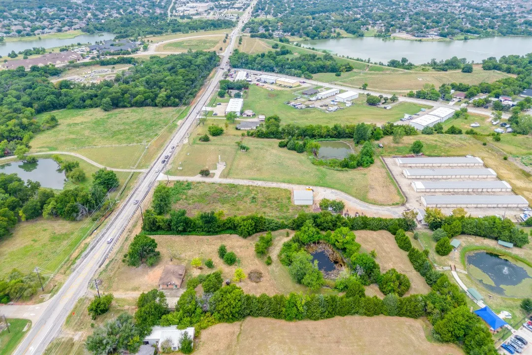 Aerial view of property's location with a nearby body of water and a tree filled landscape