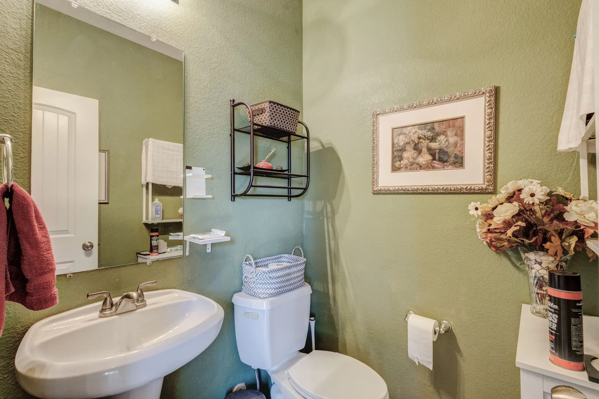 Bathroom featuring a pedestal sink with a dual-handle faucet, a wall-mounted mirror, and textured green walls