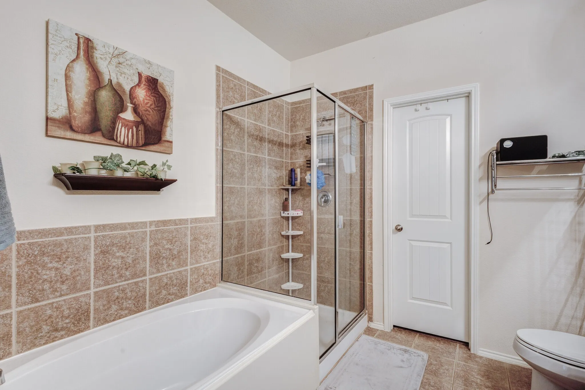 Bathroom featuring a soaking tub, glass-enclosed shower with tiled walls, and ceramic floor tiles