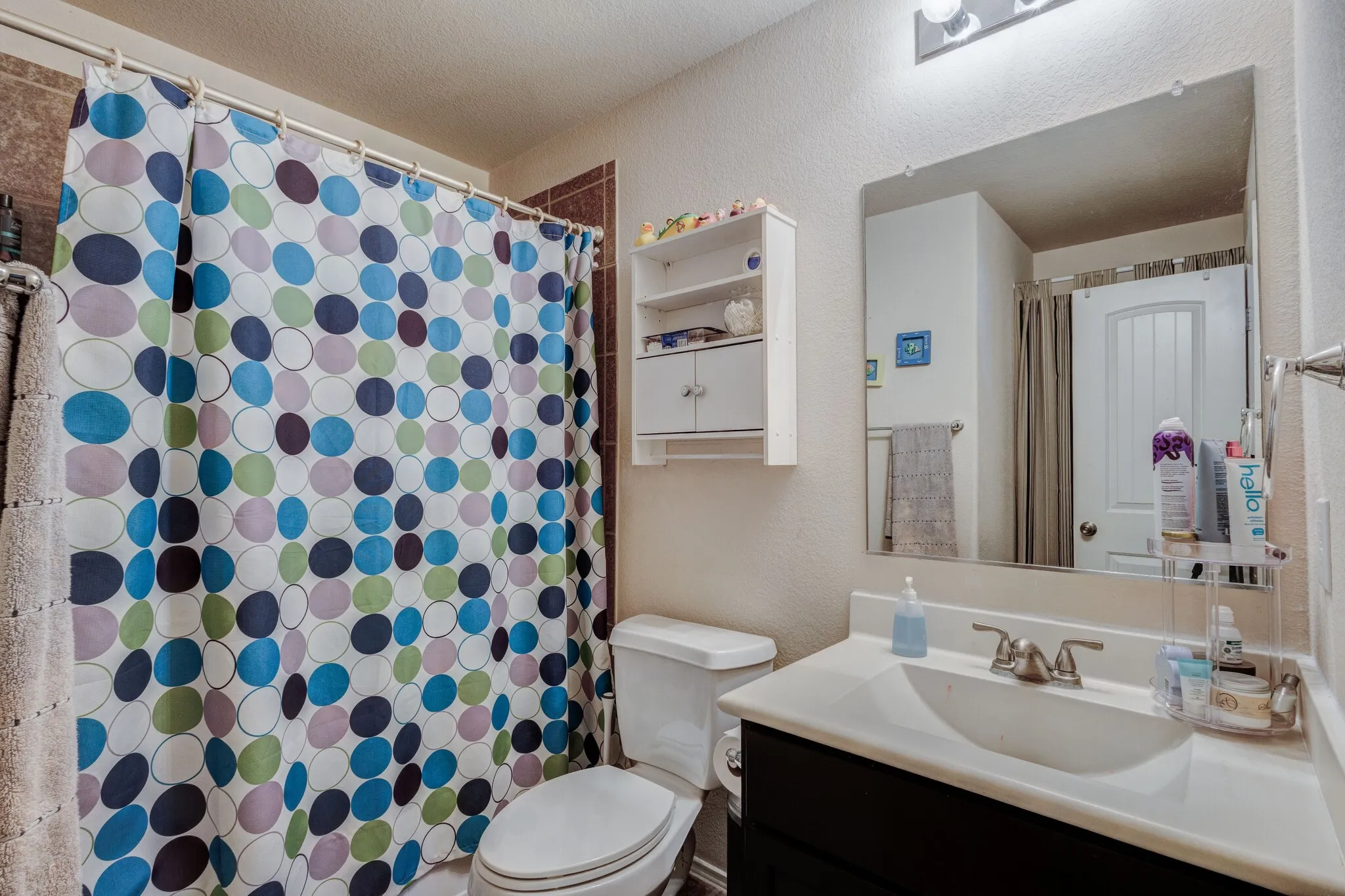 Bathroom featuring a single vanity with an integrated sink, brushed nickel faucet, and a large wall-mounted mirror
