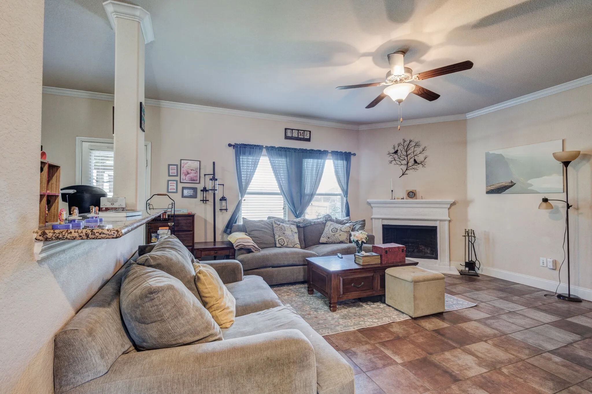 Living space featuring tiled flooring, a fireplace with a white mantel, and crown molding