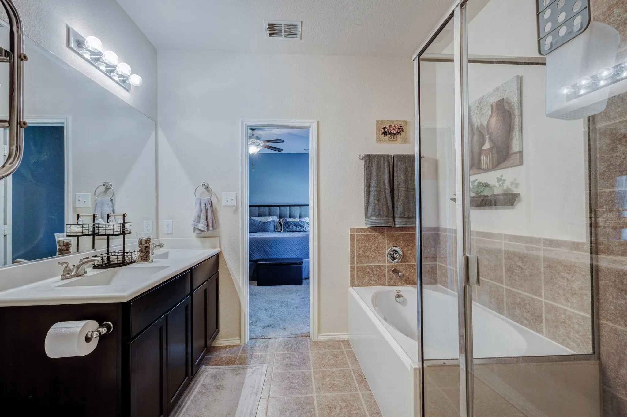 Bathroom featuring a double vanity with dark wood-finish cabinetry, a white countertop, and a large mirror