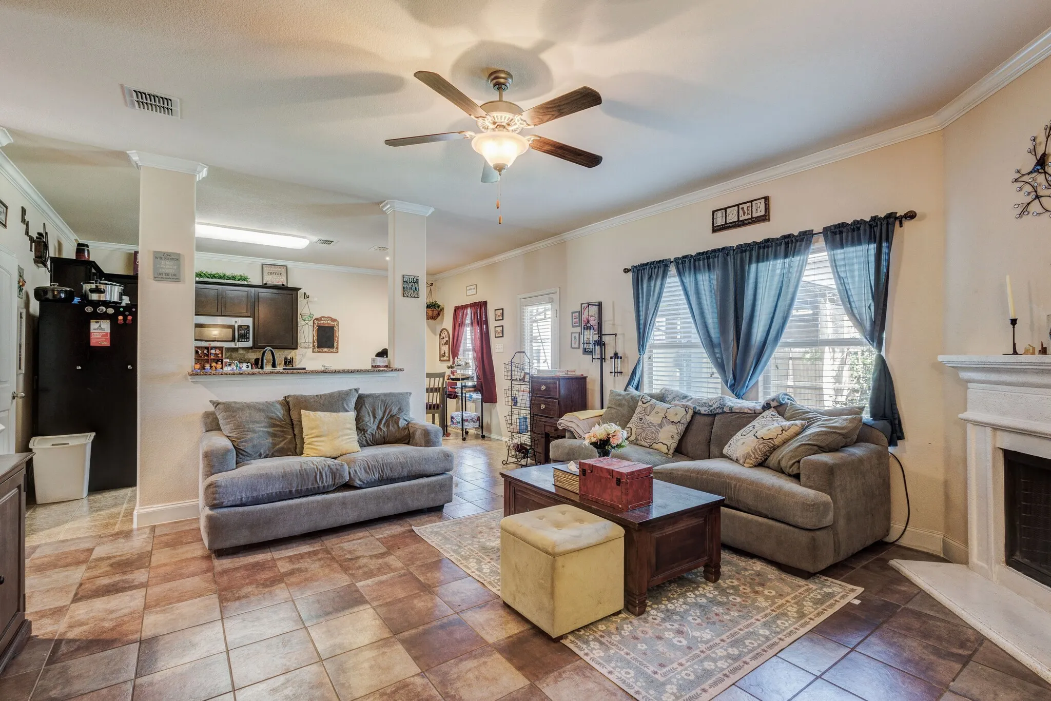 Open-concept living area featuring a ceiling fan, crown molding, and tiled flooring