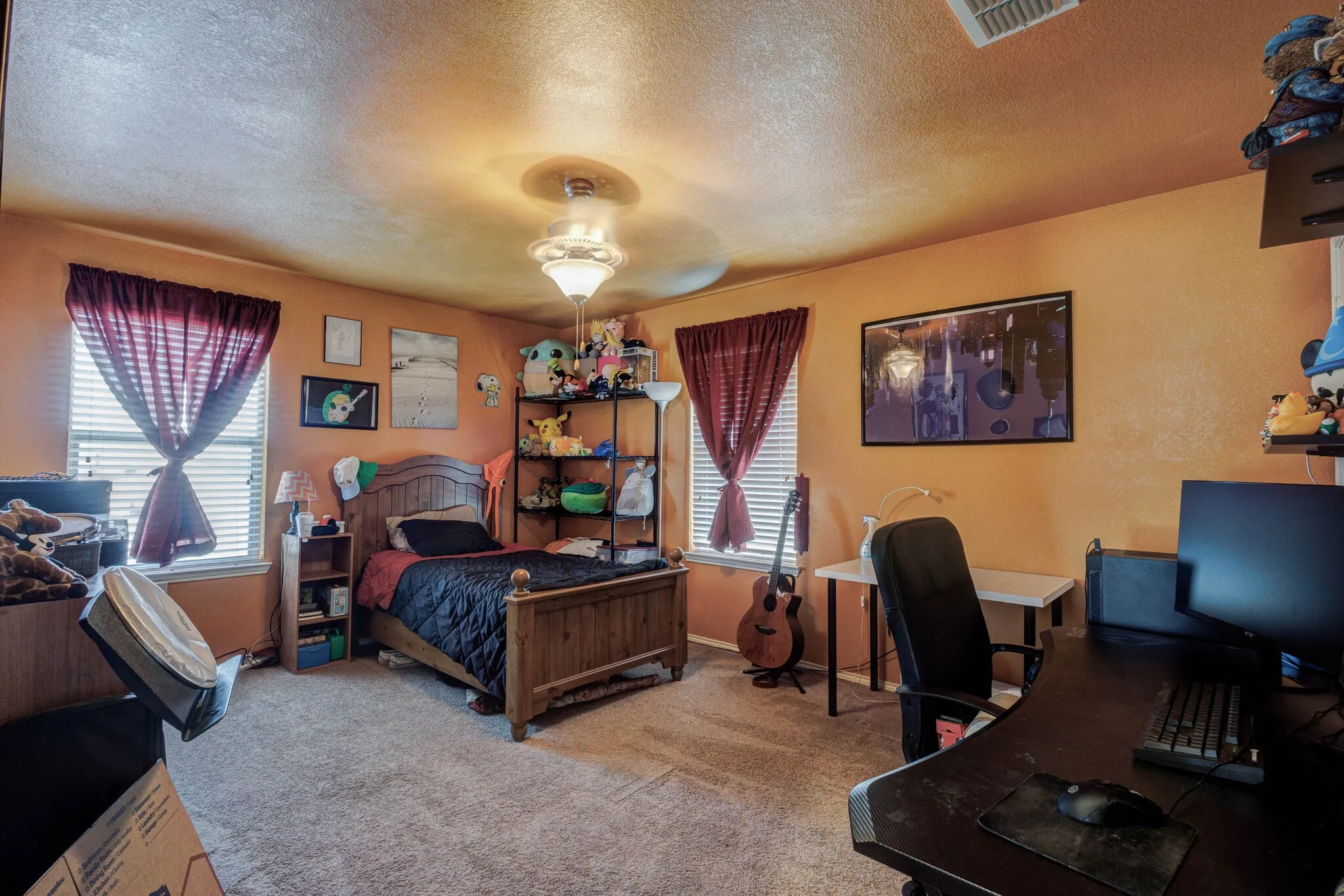 Carpeted bedroom featuring a ceiling fan, two windows with blinds, and a built-in shelf