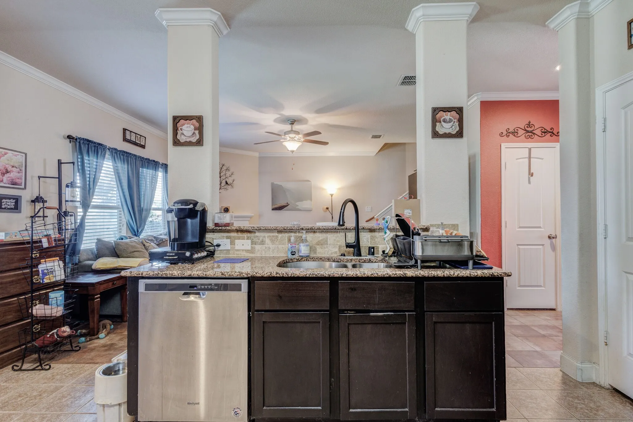 Kitchen with dark wood-finish cabinetry, light speckled countertops, and a stainless steel dishwasher