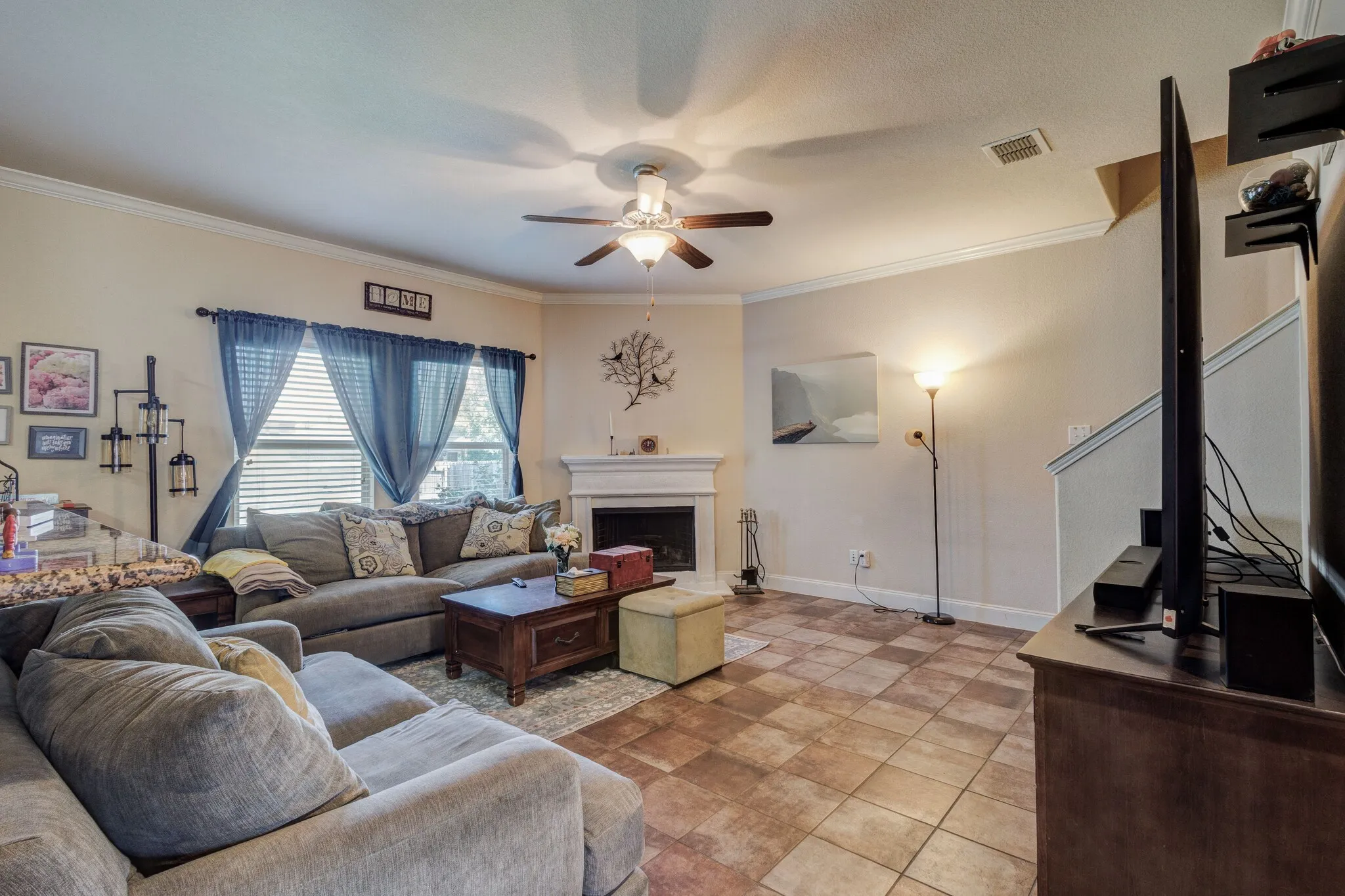 Living area featuring expansive tile flooring and a corner fireplace with a white mantel