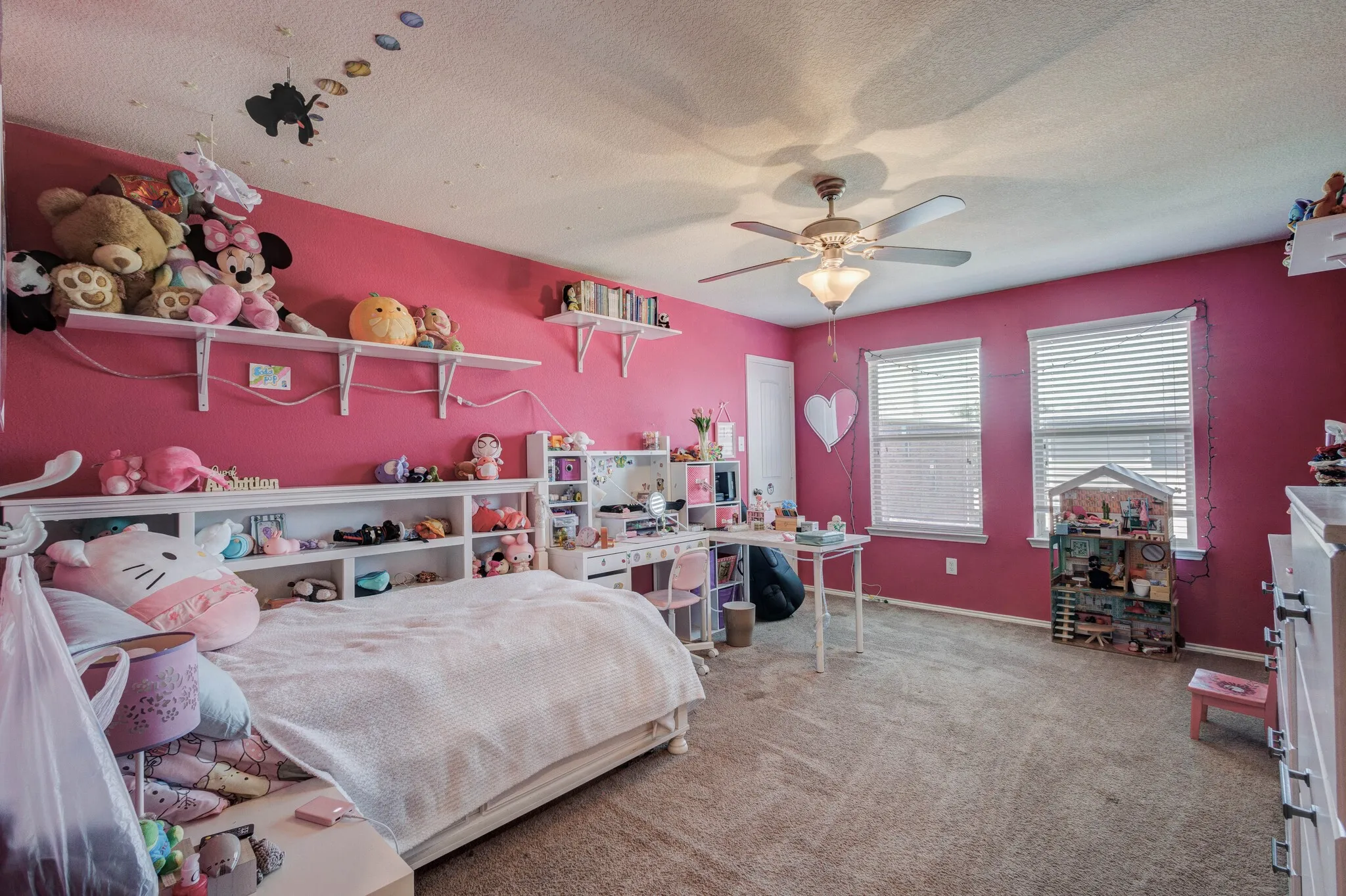 Carpeted room featuring two windows with horizontal blinds, a ceiling fan with integrated lighting, and a white door frame