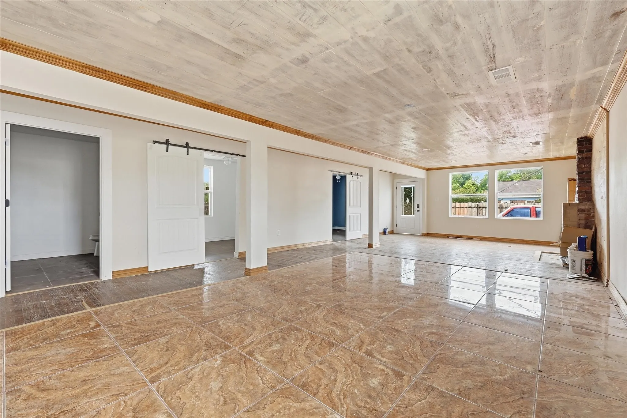 Spacious room featuring glossy tile flooring, white walls, and a wood-finish ceiling