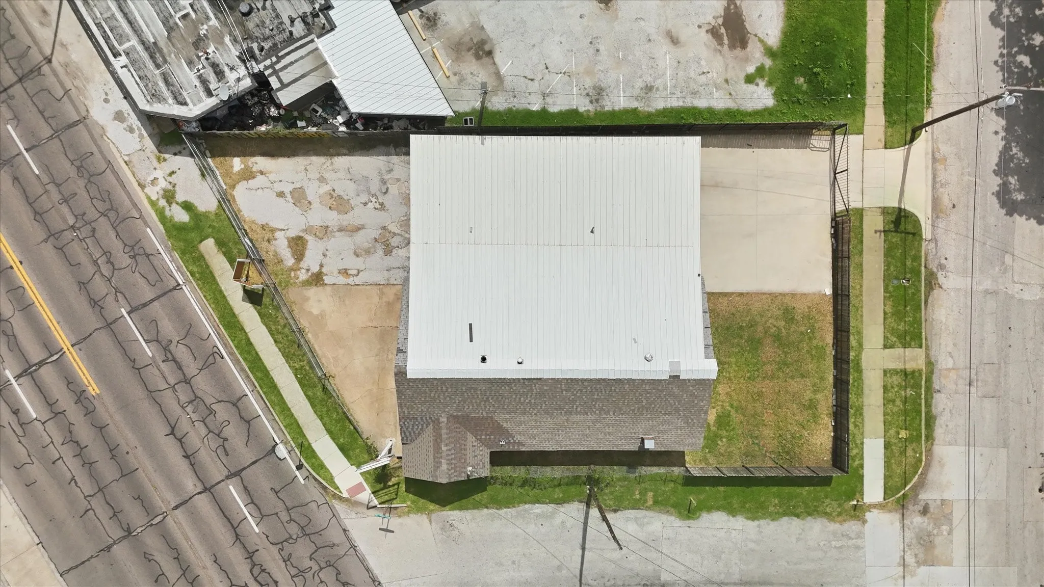 Commercial property featuring a white corrugated metal roof and a brown shingled roof section