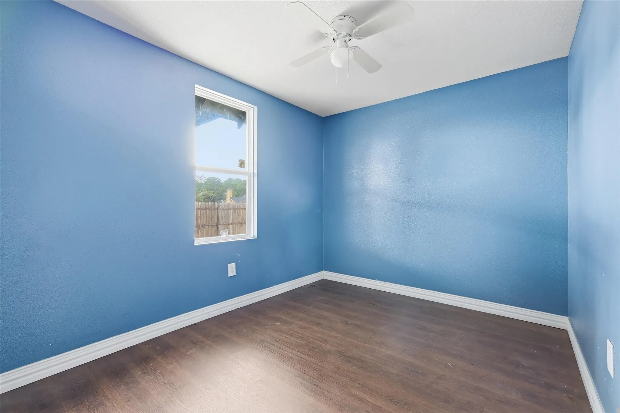 Room featuring wood-finish flooring, a white ceiling fan, and white baseboards