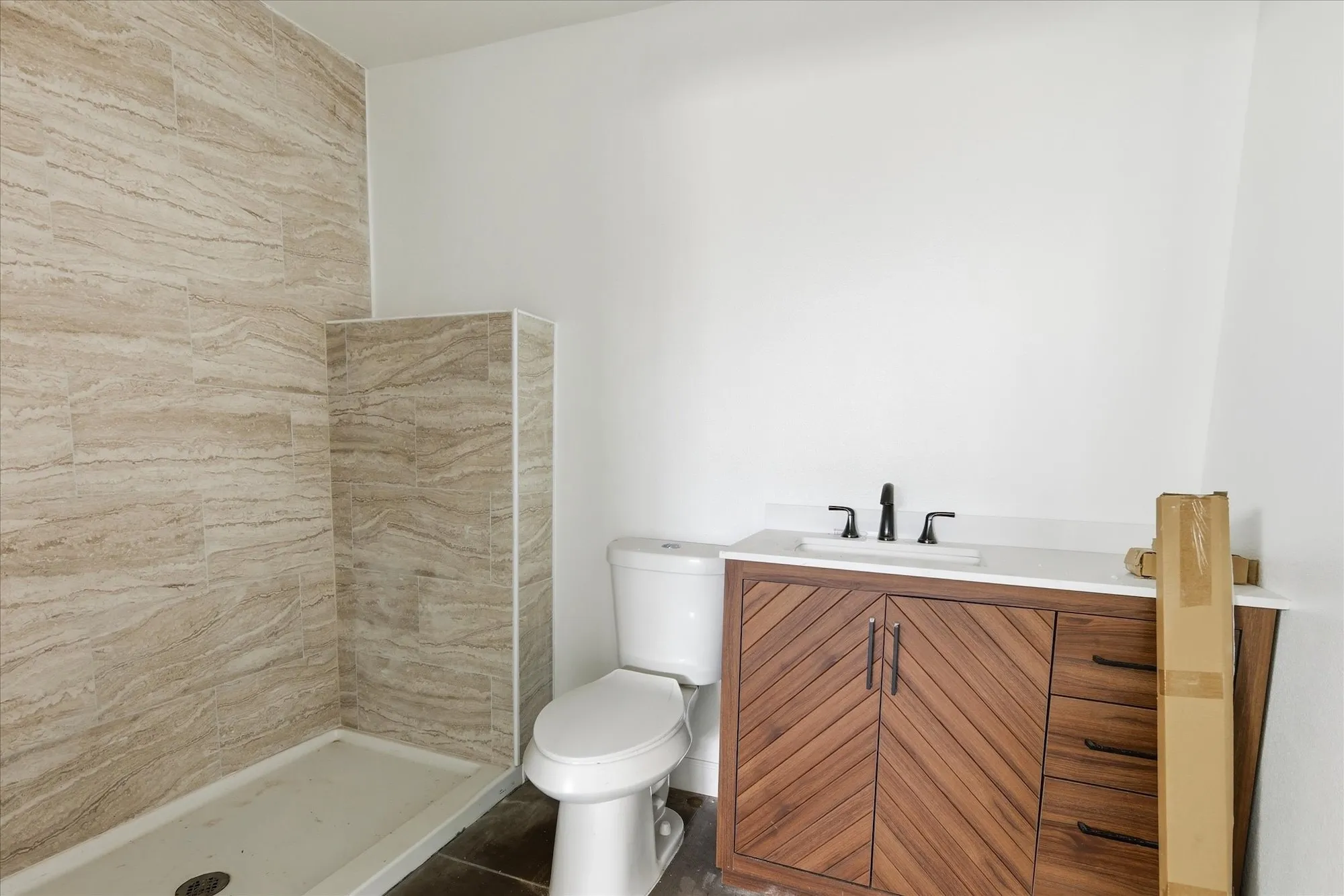 Contemporary bathroom featuring a tiled shower stall, a toilet, and a vanity with a white countertop